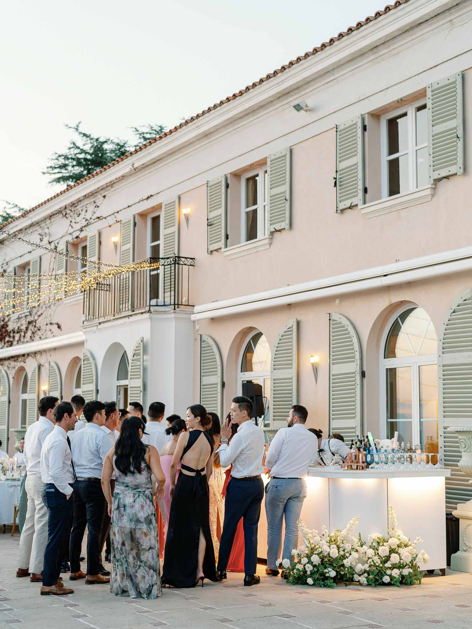 Cocktail hour on Mediterranean villa terrace with guests at white bar counter