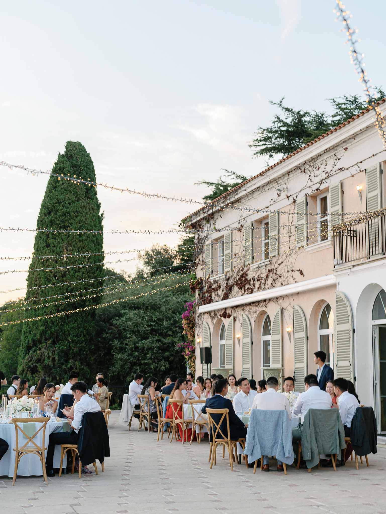 Wedding reception dinner on stone terrace courtyard at historic pink building with string lights