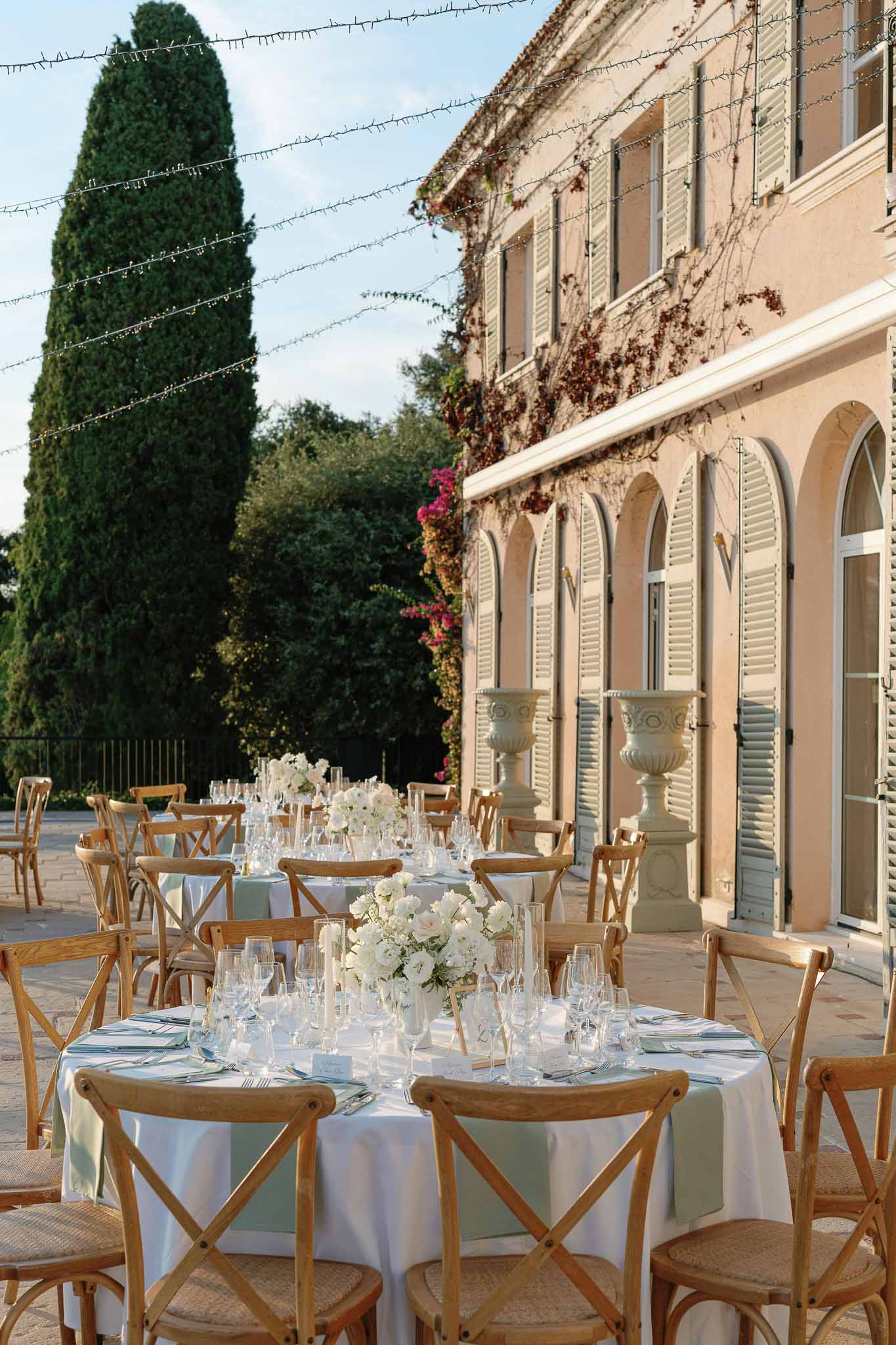 Outdoor reception terrace setup with ivory linens and white floral centerpieces at historic stone venue