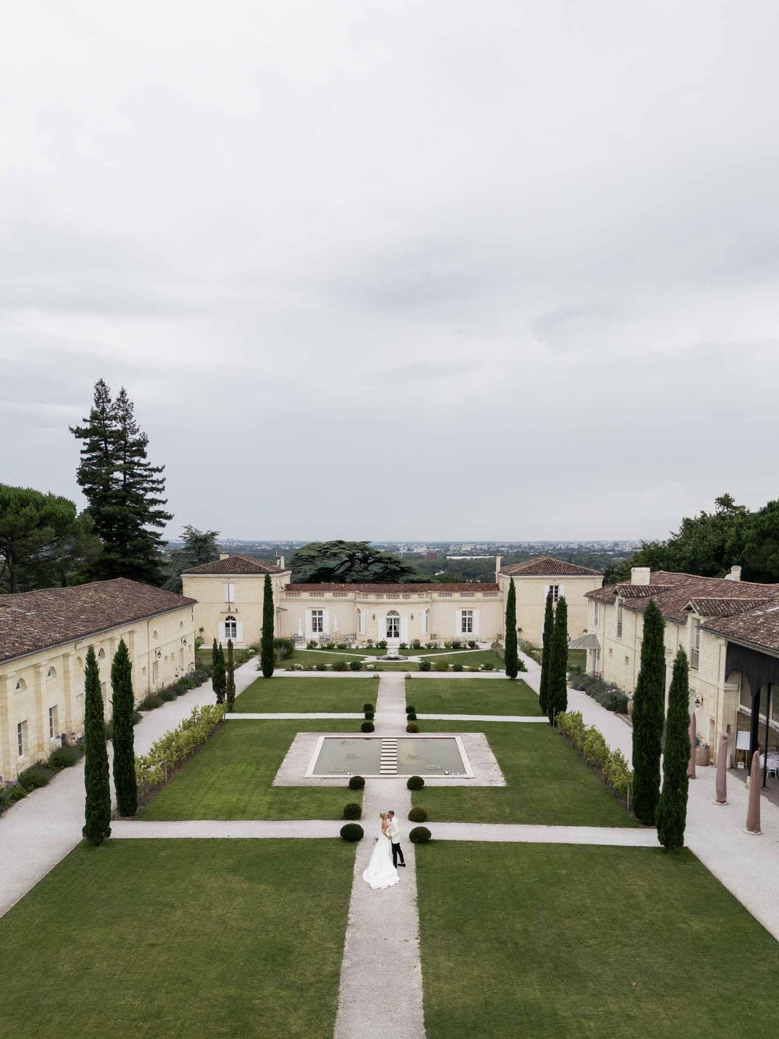 Bride and groom aerial portrait in formal courtyard of classical French château estate