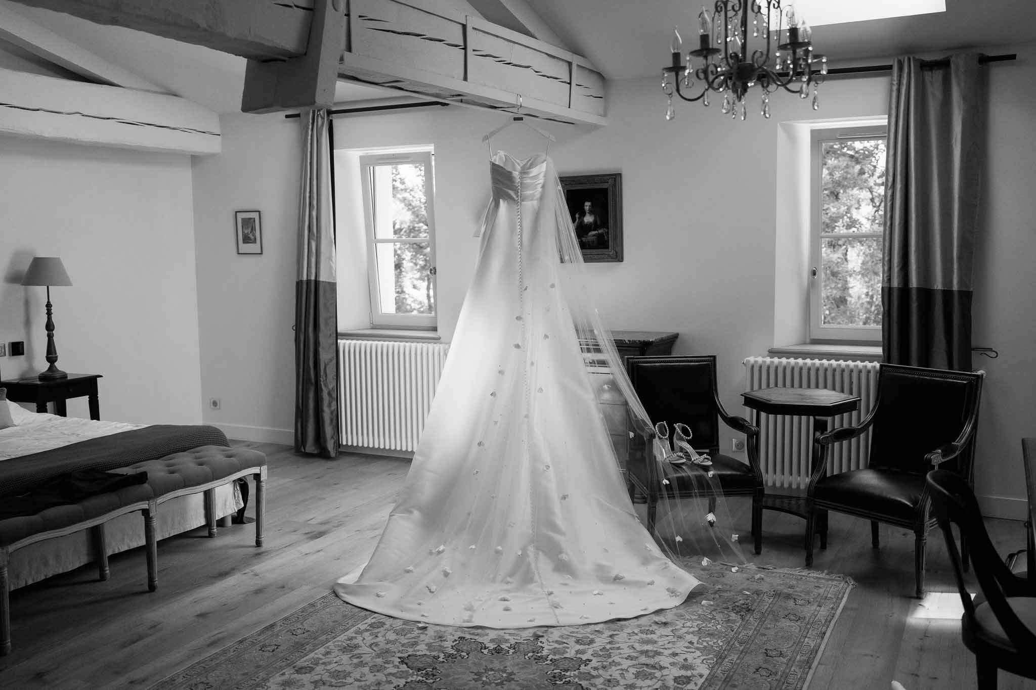 Bridal gown on dress form in elegant bedroom suite with exposed beams and crystal chandelier