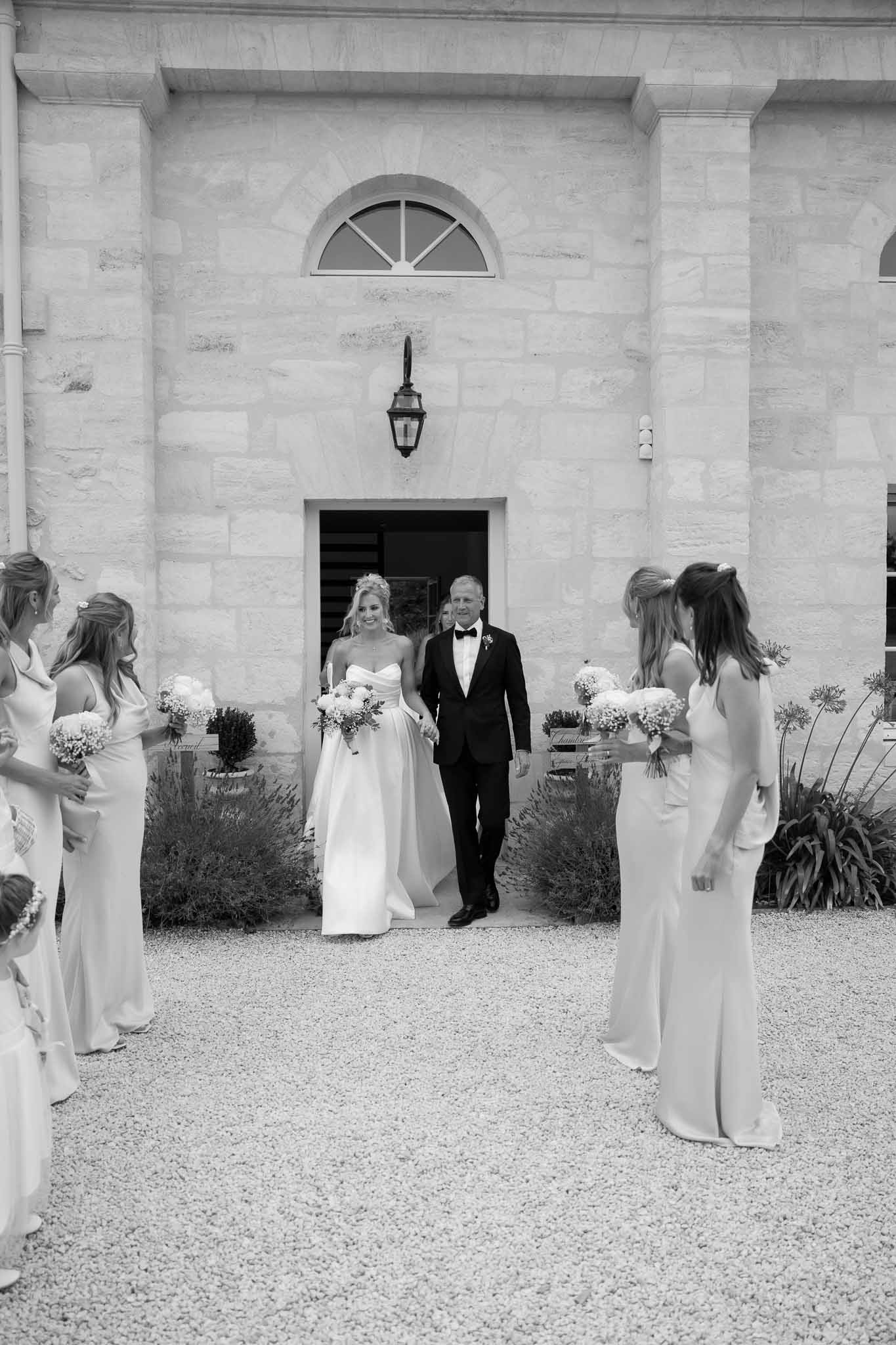 Bride and groom walking with bridesmaids in courtyard at classical stone building venue