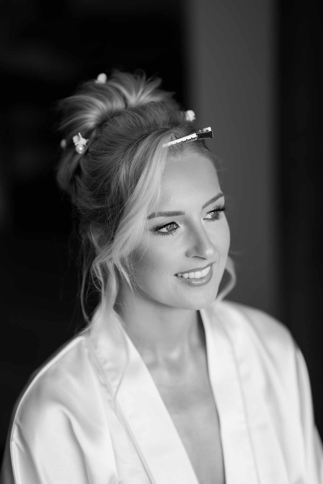 Black and white close-up portrait of bride with upswept hair and pearl clips during wedding preparation