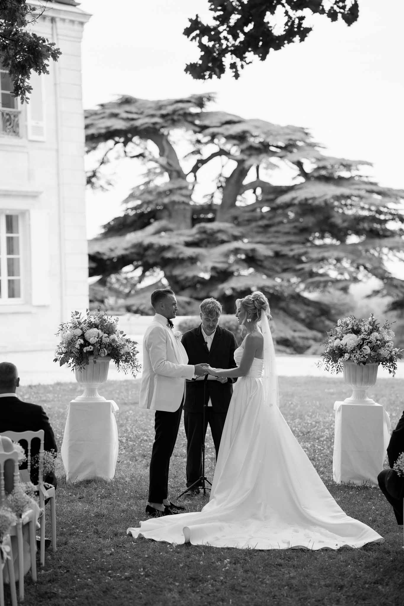 Bride and groom exchanging vows during outdoor ceremony at classical white building venue