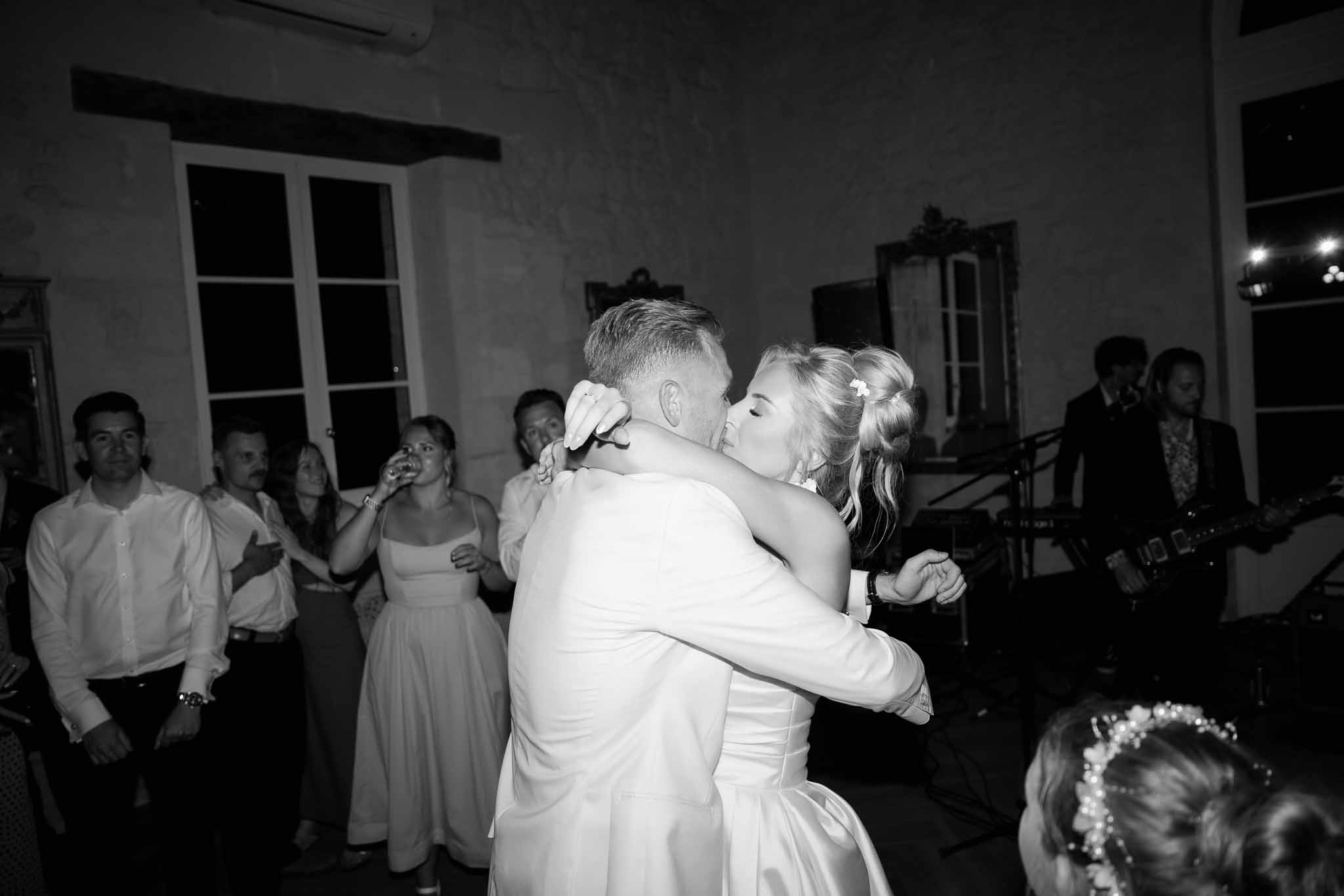 First dance with bride and groom surrounded by wedding guests at indoor reception venue