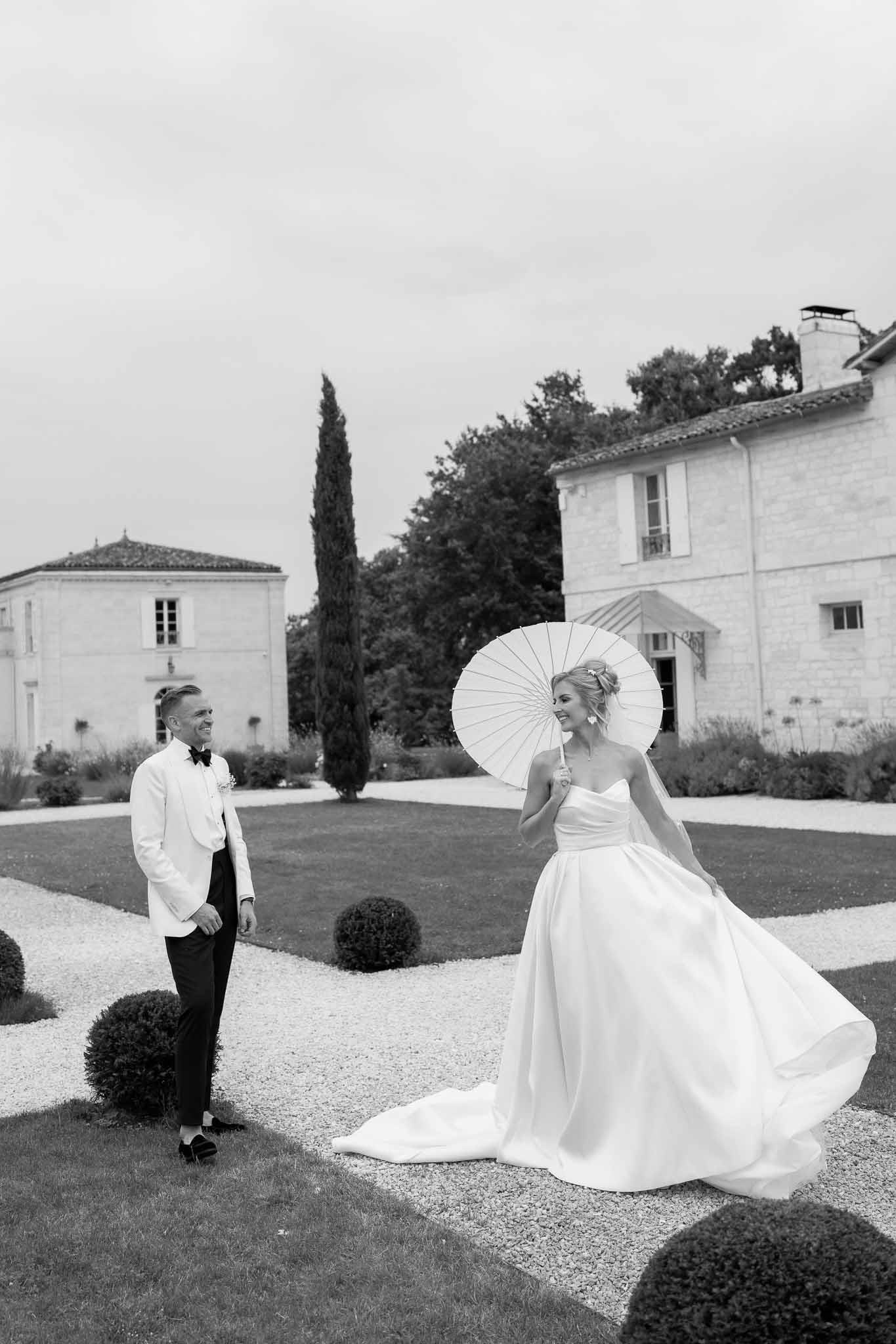 Bride and groom in formal attire posing on estate grounds with classical architecture