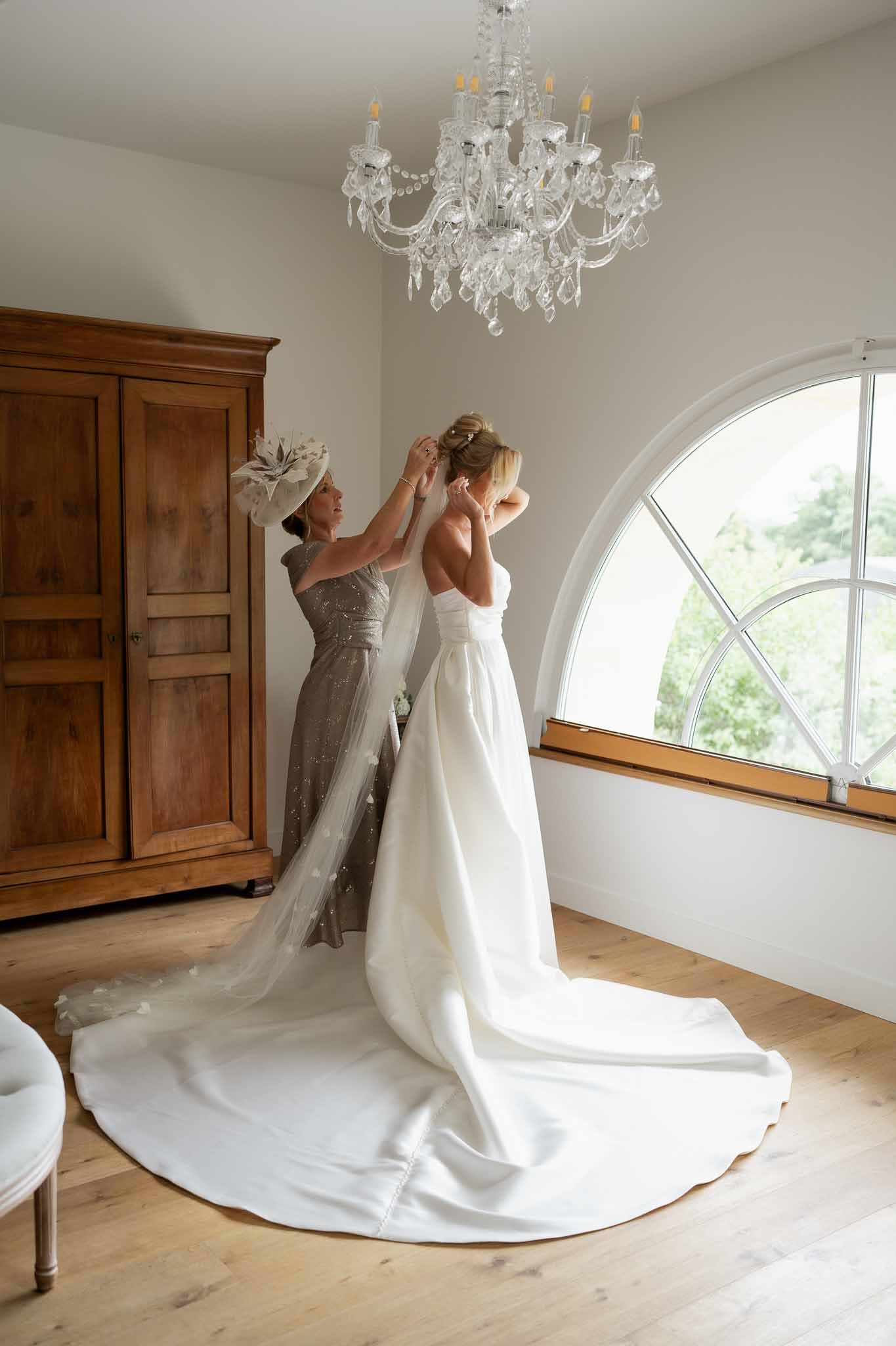 Bride being helped with veil during getting ready in elegant classical interior room