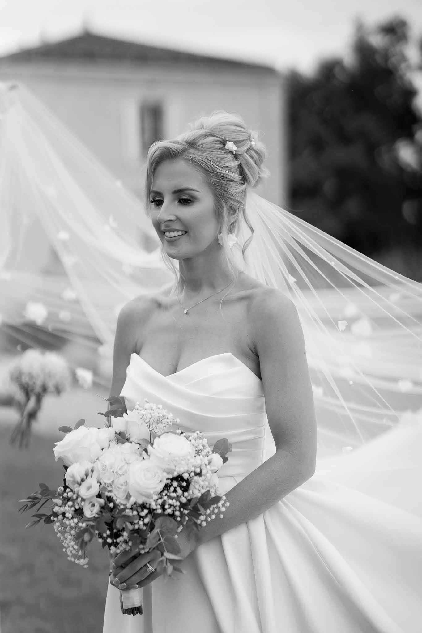 Black and white bridal portrait of bride in strapless gown with veil at classical outdoor venue