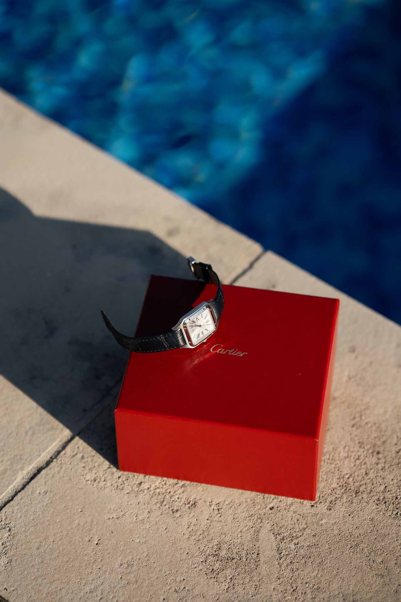 Cartier watch on red box by swimming pool at luxury wedding venue