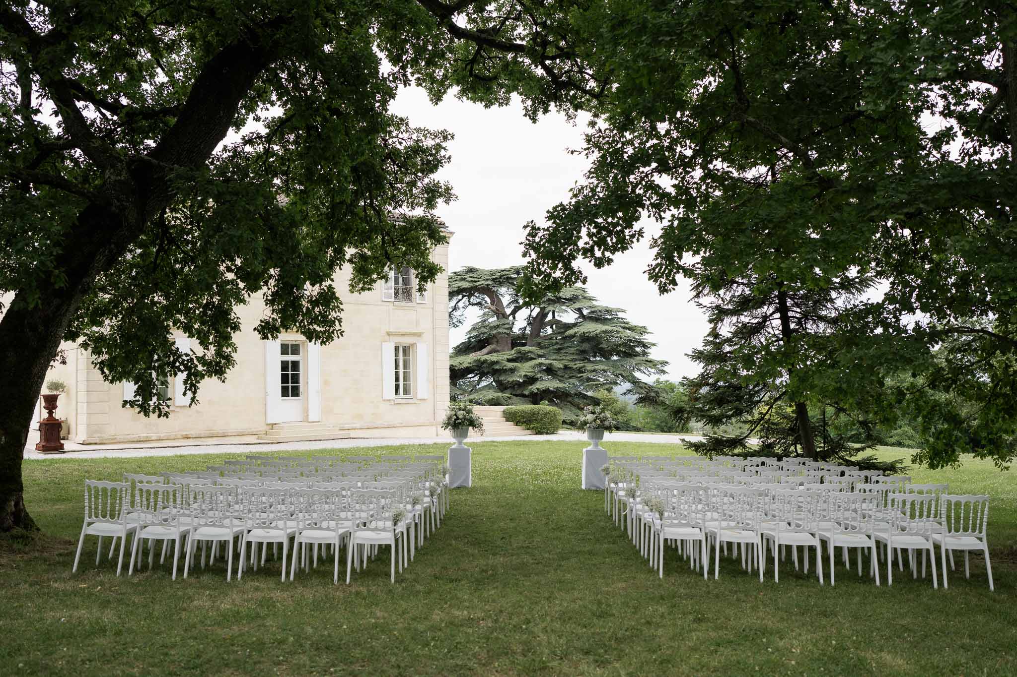 Outdoor wedding ceremony setup with white chairs on lawn at neoclassical venue