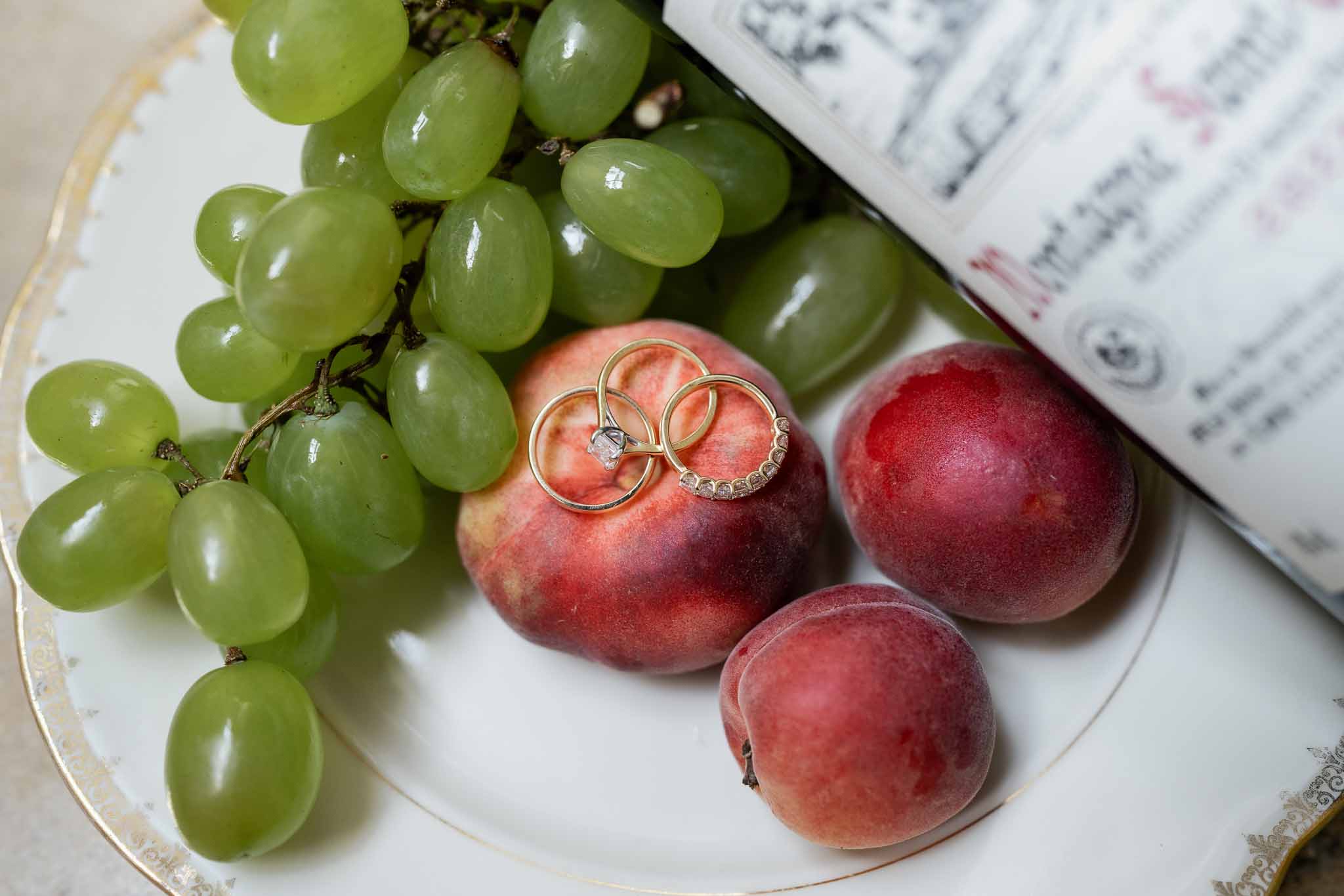 Wedding rings arranged on decorative plate with fruit in styled flat lay composition