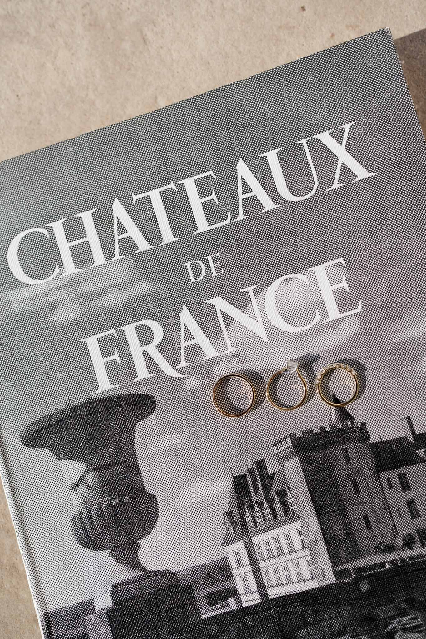 Gold wedding rings on château venue guide program with architectural photograph