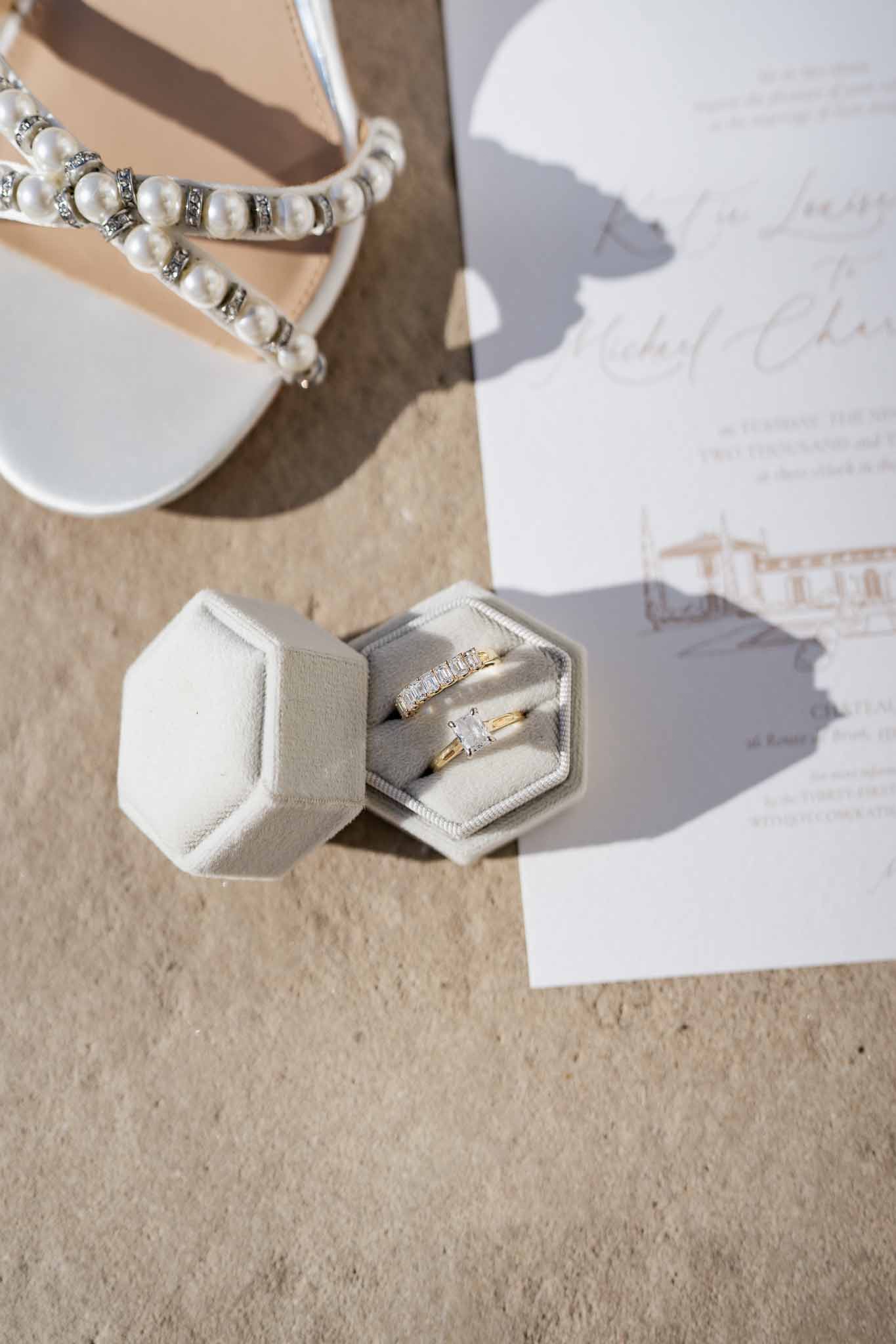 Wedding rings, shoes, and invitations arranged in flat lay composition on neutral surface