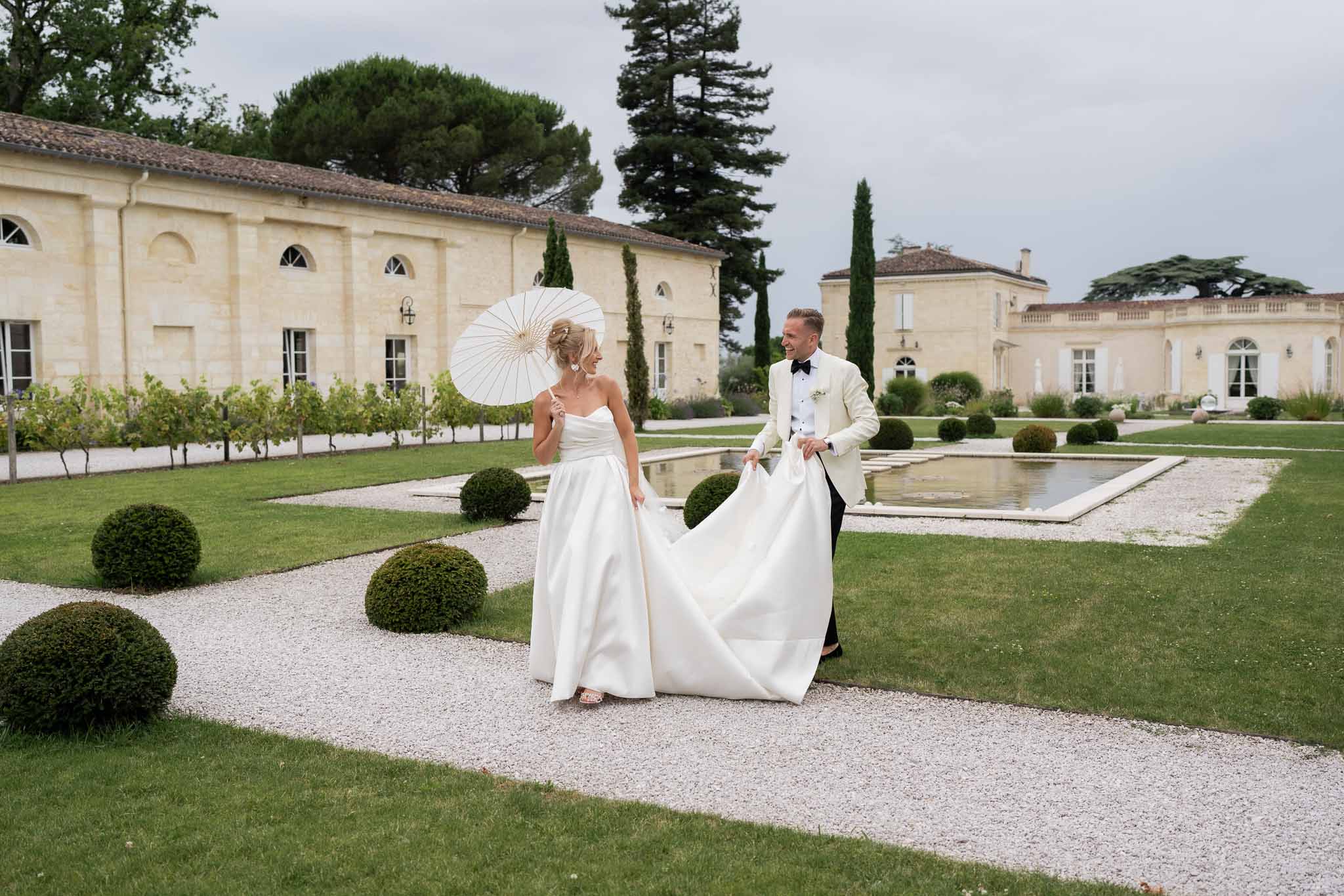 Bride and groom walking together in courtyard of French neoclassical estate during portrait session