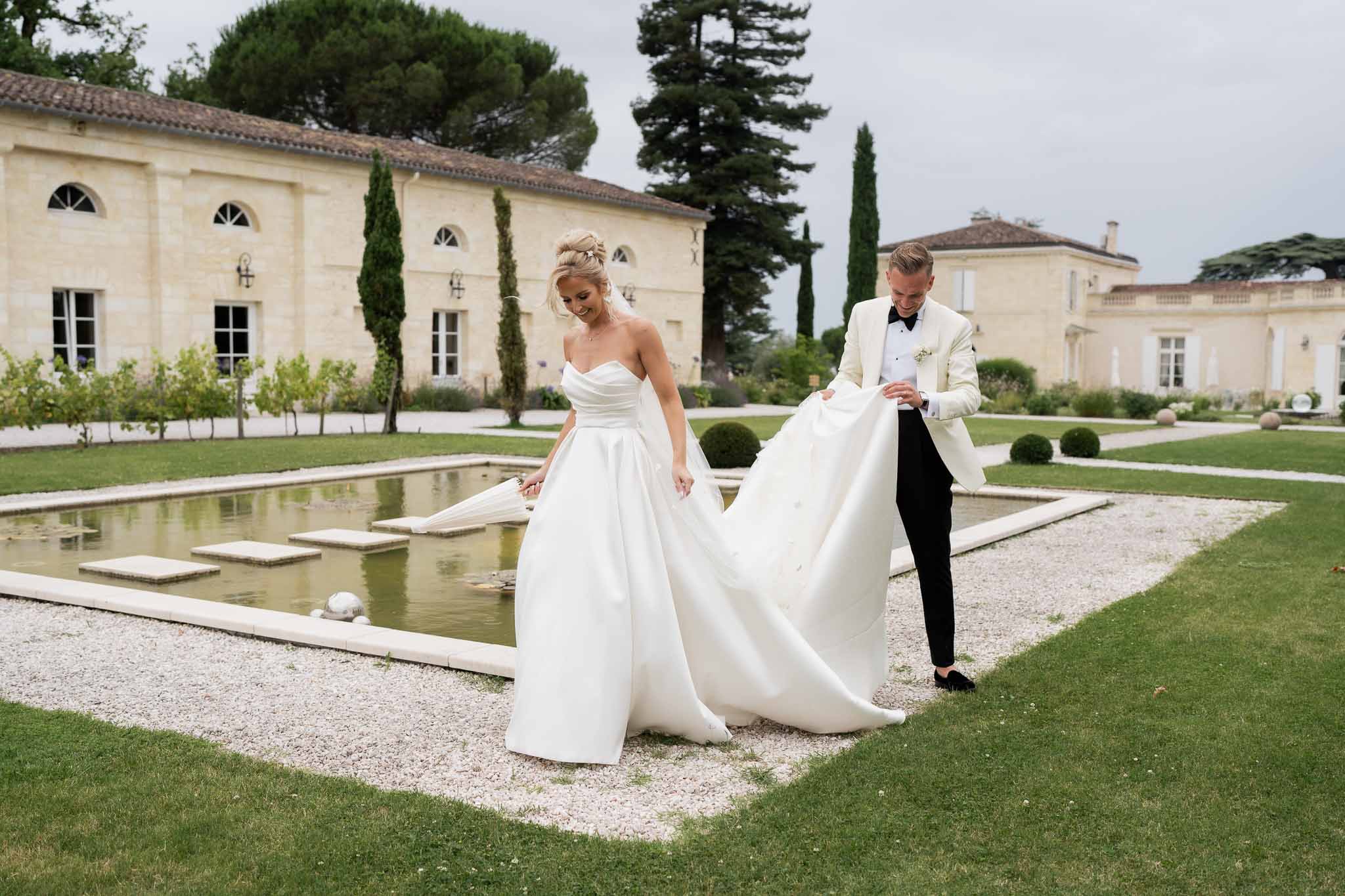 Bride and groom formal portrait in classical estate garden with reflecting pool and neoclassical architecture
