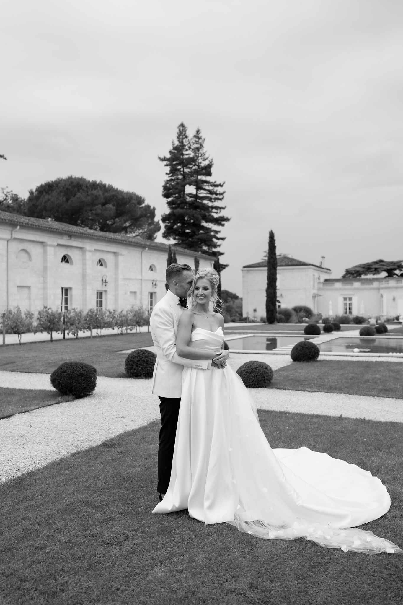 Bride and groom portrait in formal gardens at classical estate with topiary and reflecting pool