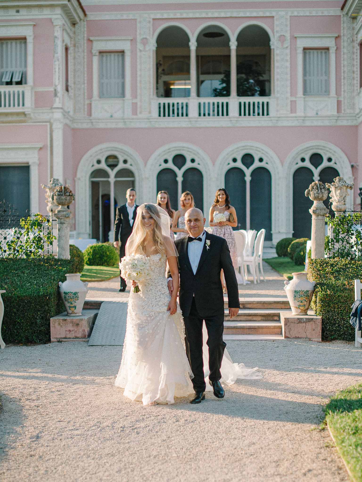 Bride and groom walking together in classical courtyard with neoclassical architecture and manicured gardens