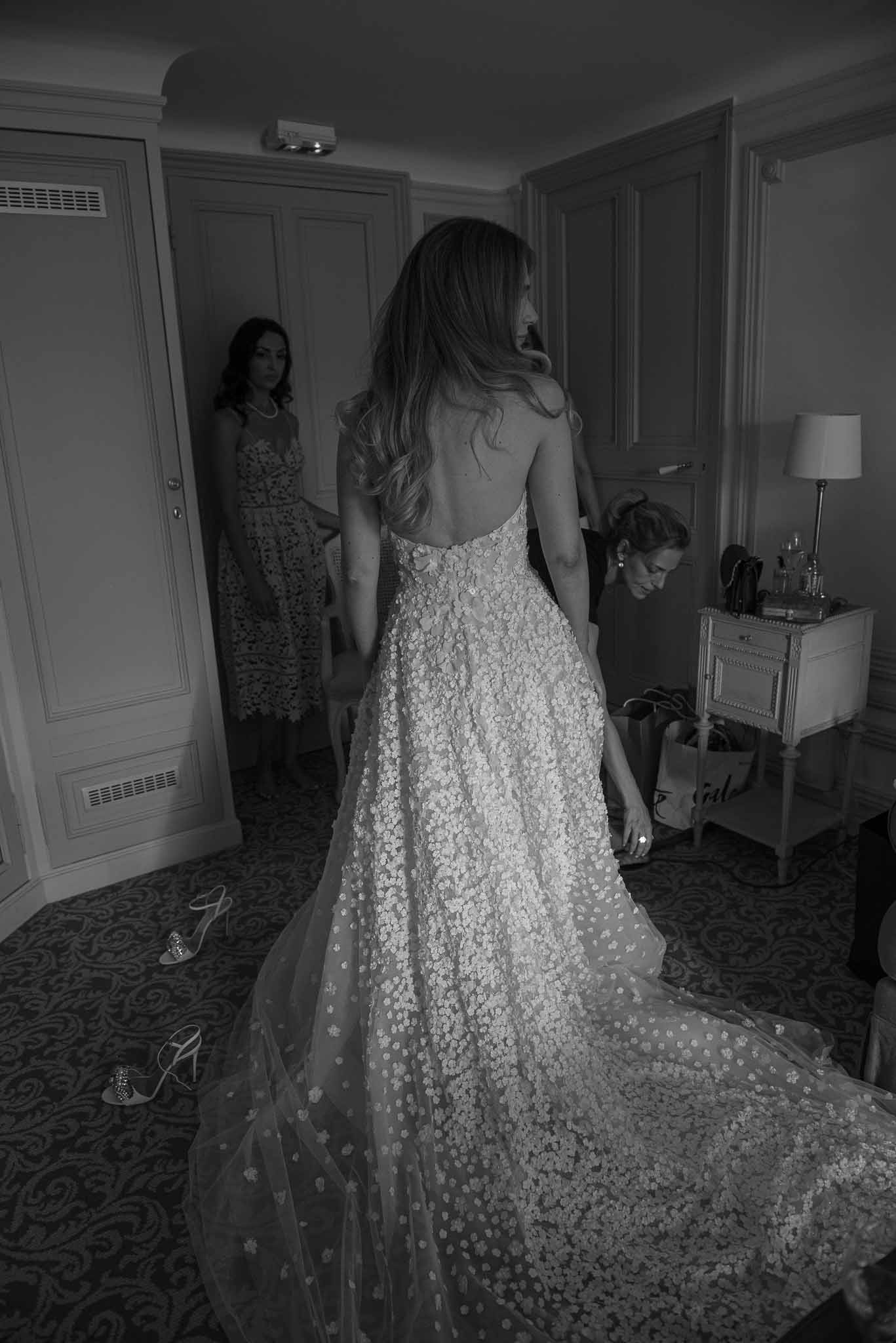 Bride in beaded wedding gown with bridesmaids during getting ready in elegant hotel suite