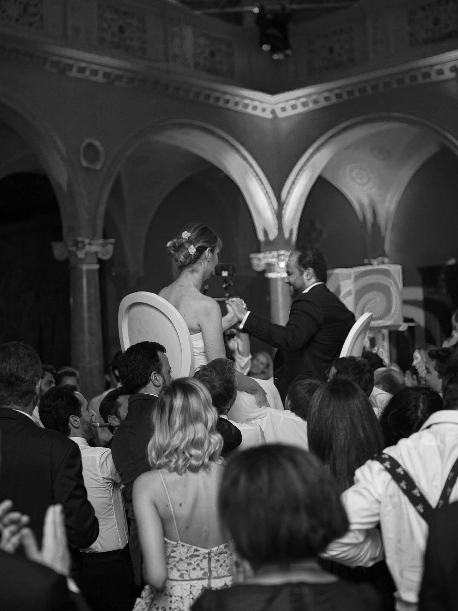 First dance moment with bride and groom surrounded by seated guests in grand classical interior space