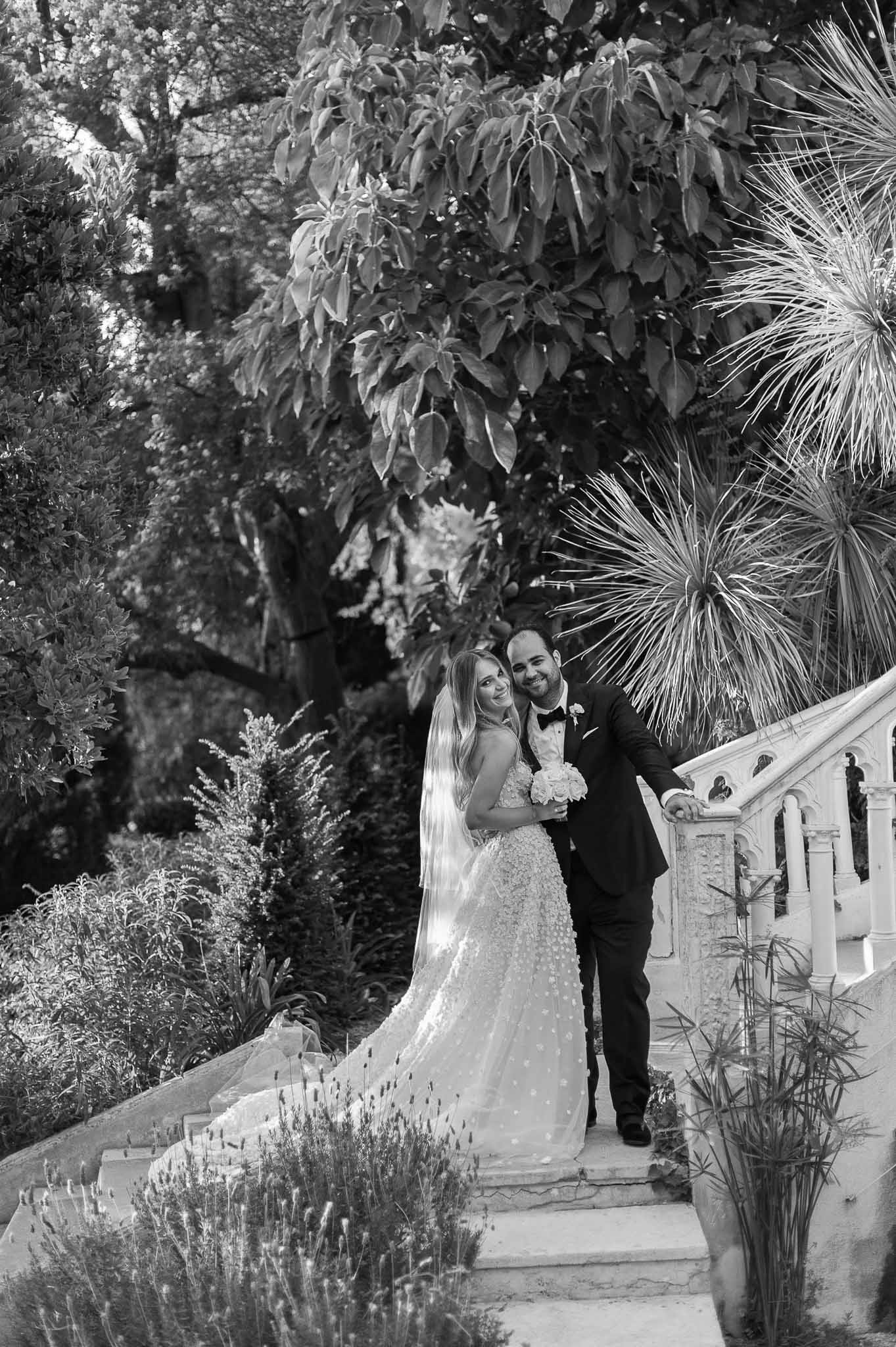 Bride and groom walking together along stone pathway in garden setting