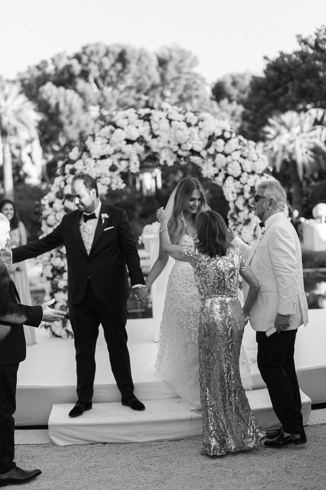 Couple interacting with guests during reception with floral backdrop