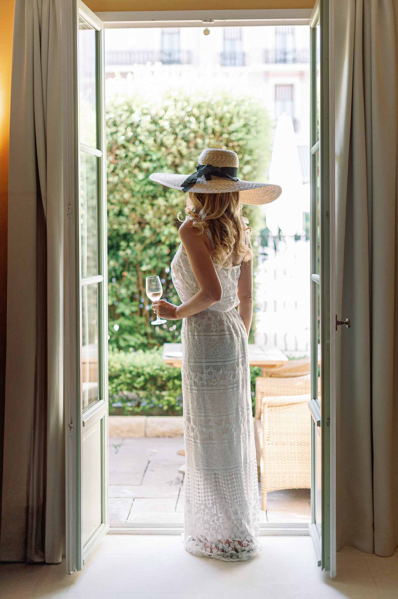 Bride in lace wedding dress standing in French doorway overlooking Parisian courtyard