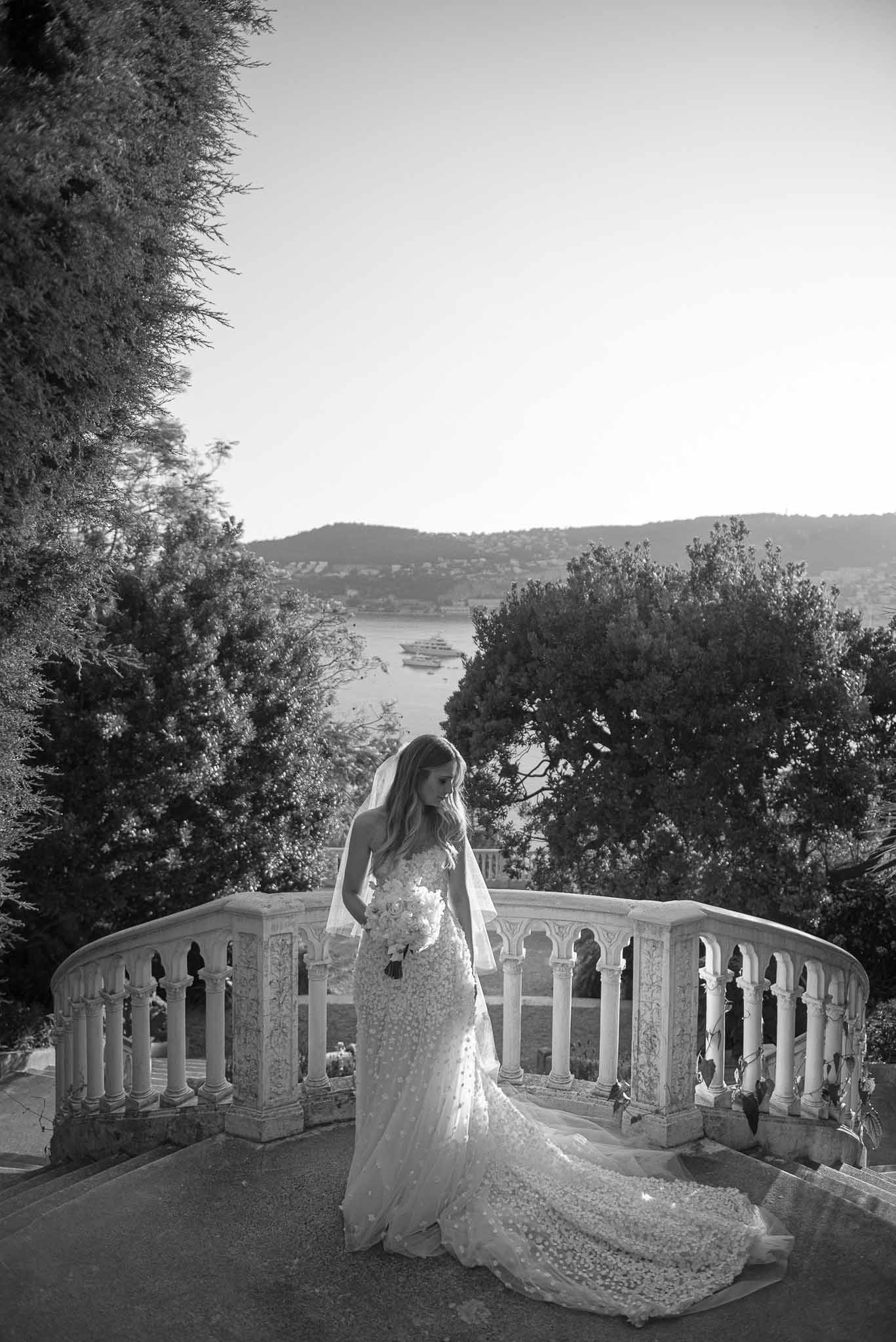 Bride in lace wedding dress on stone balcony overlooking river valley at classical venue