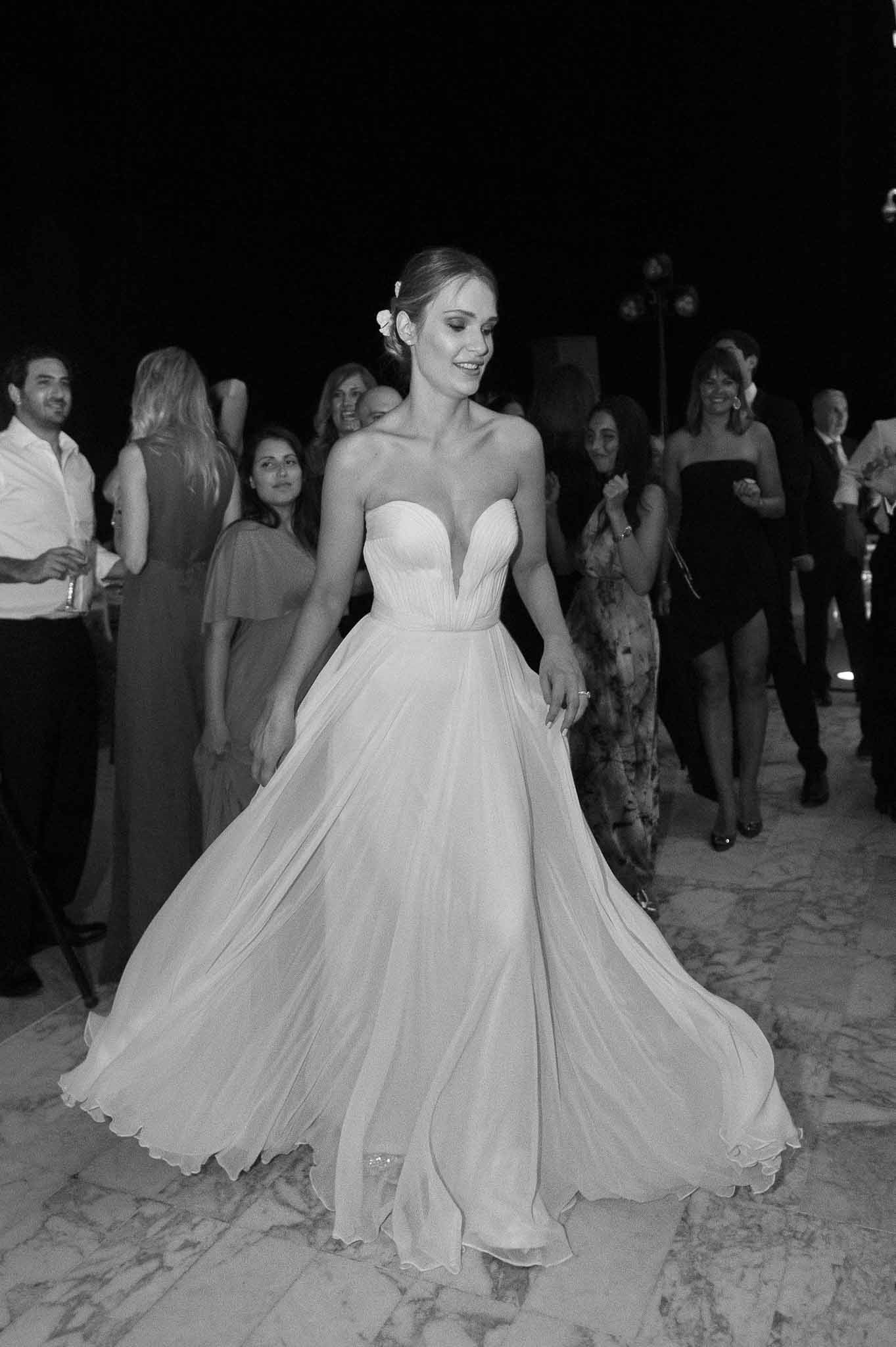 Bride surrounded by guests during evening beach wedding reception