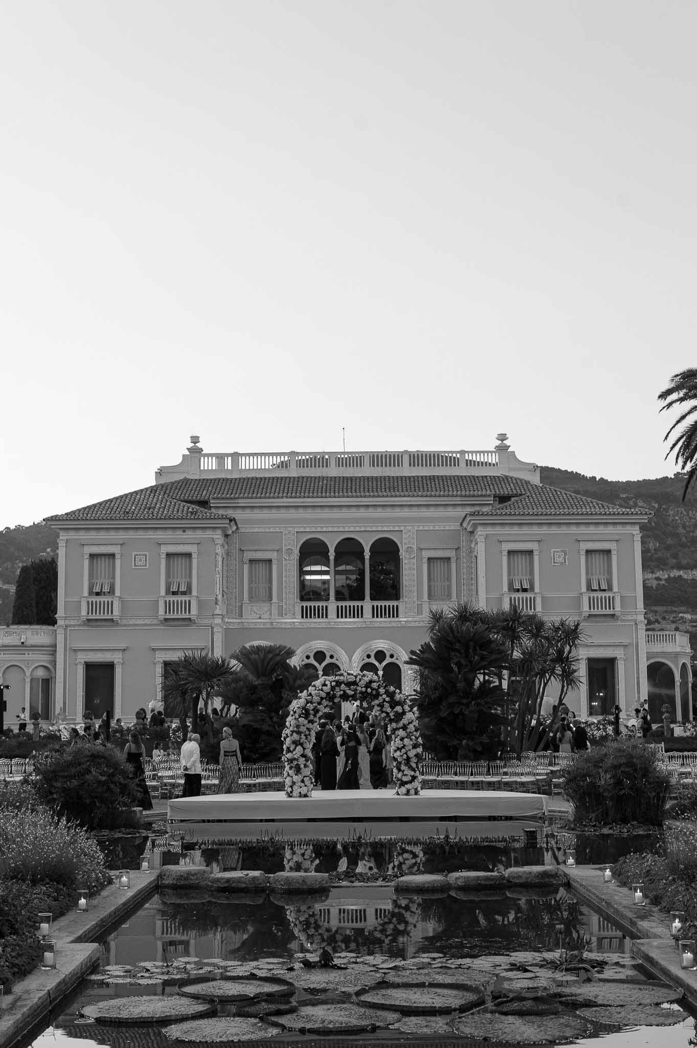 Wedding ceremony with floral arch at classical villa with reflecting pool and formal gardens