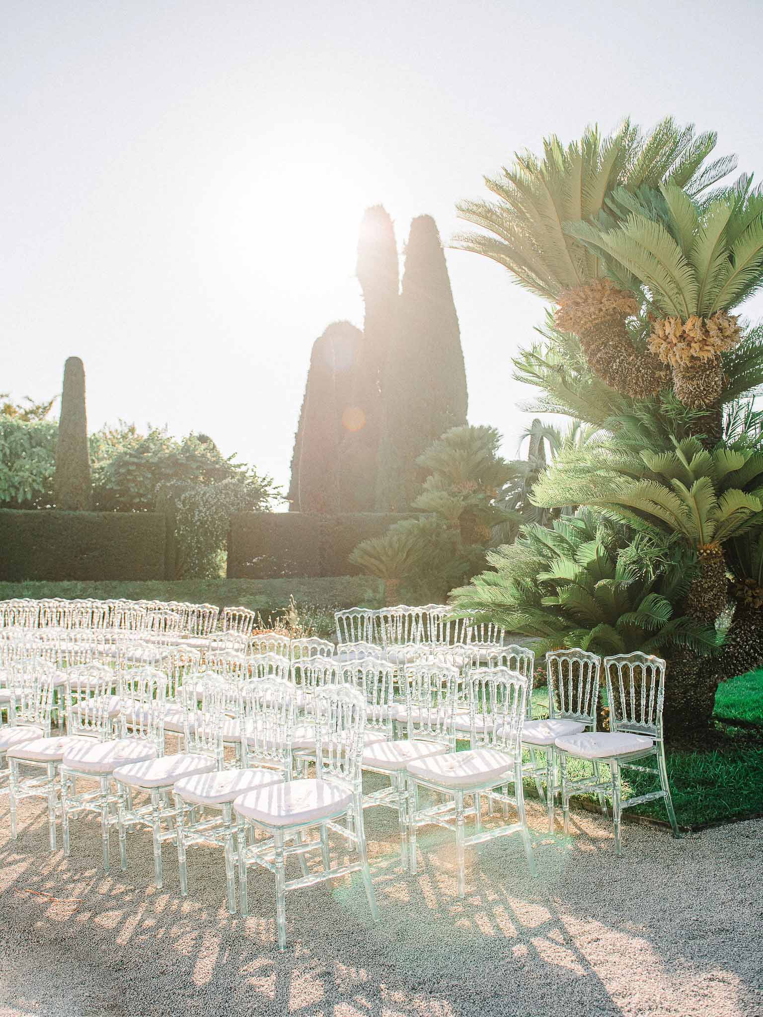 Outdoor ceremony setup with white chairs in Mediterranean garden venue with cypress trees