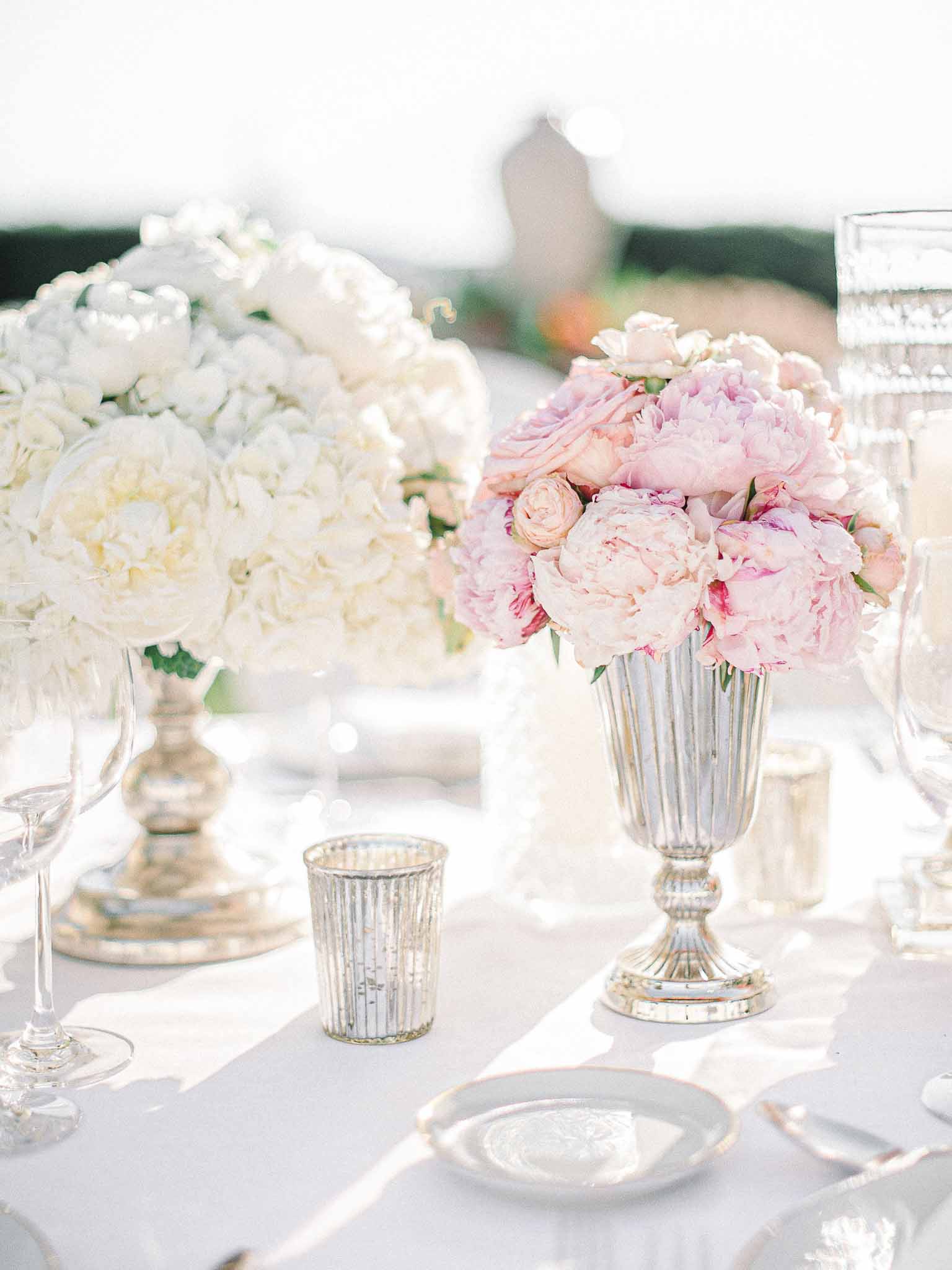 Reception tablescape with floral centerpieces and place settings at outdoor garden wedding