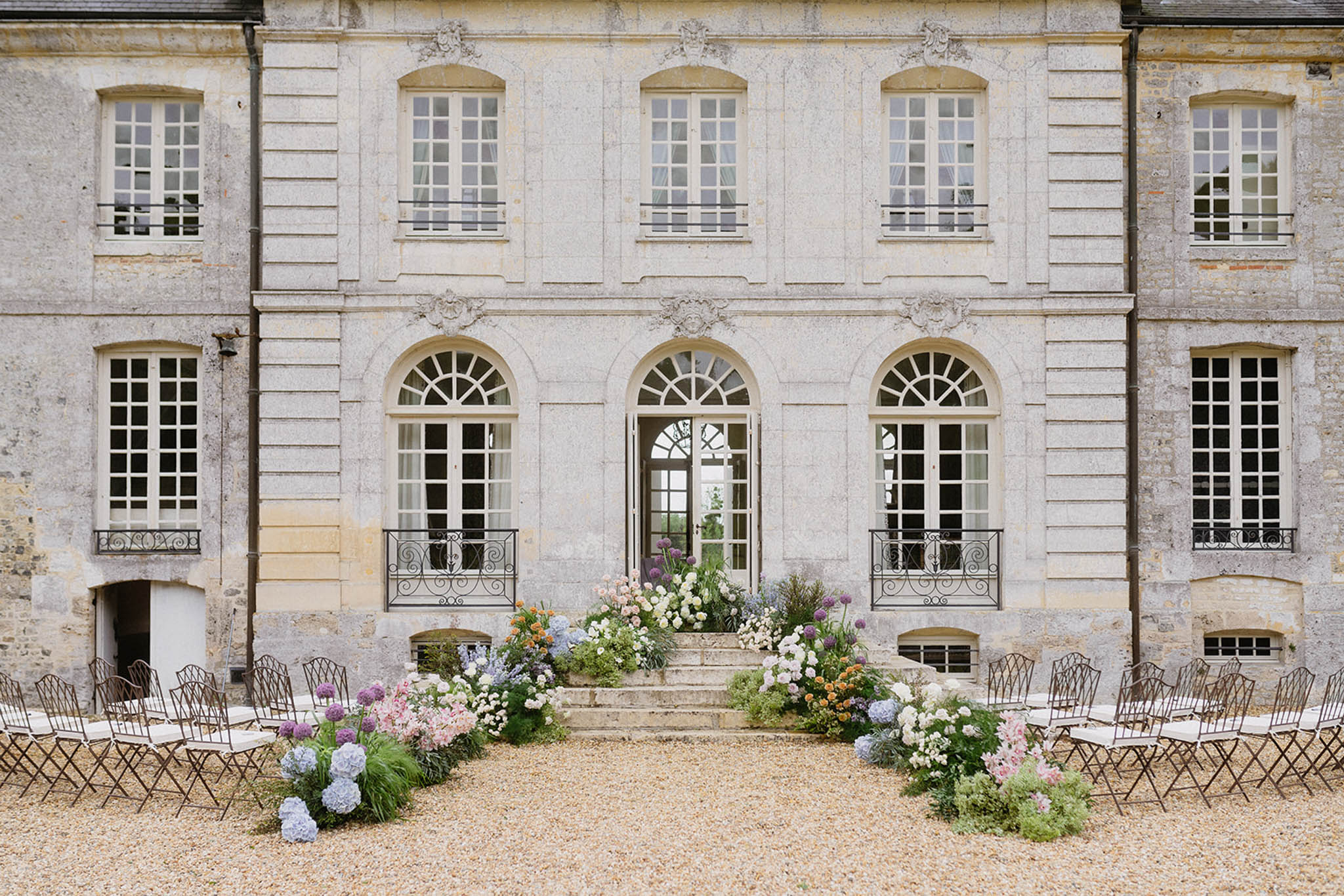 Wedding ceremony setup in château courtyard with floral aisle and stone architecture