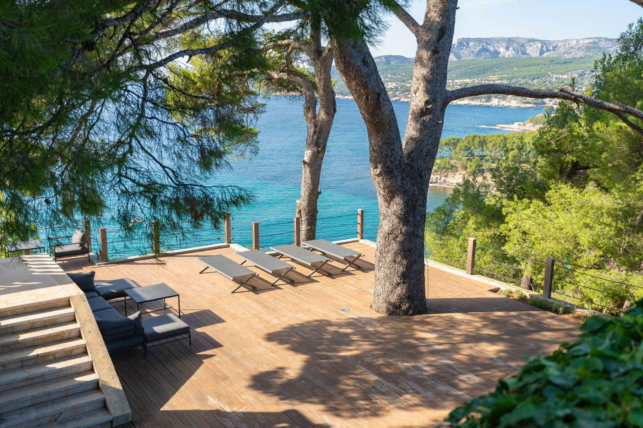 Wooden deck terrace with sun loungers overlooking turquoise Mediterranean bay near Cassis