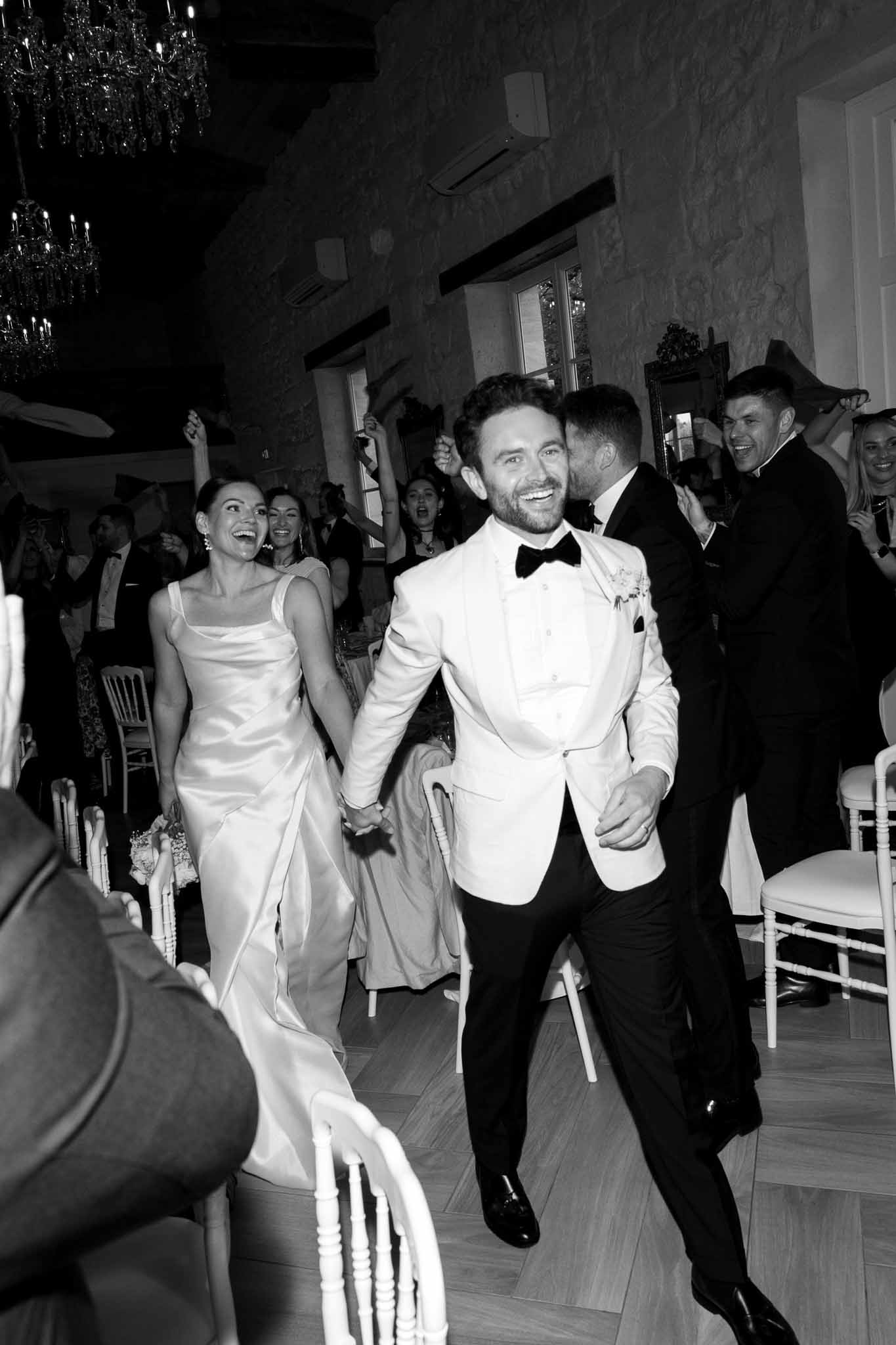 Couple's first dance surrounded by guests in elegant indoor ballroom reception