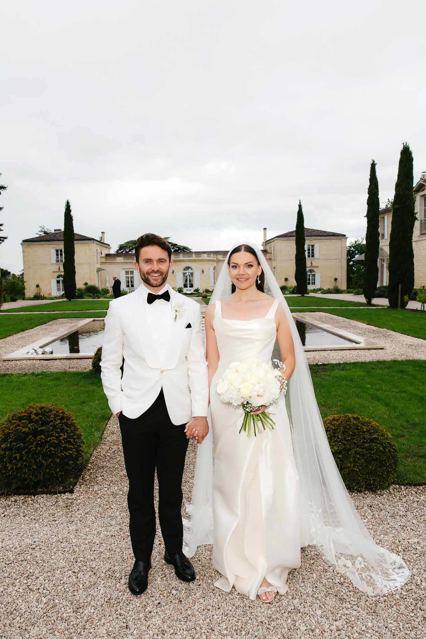 Bride and groom formal portrait at neoclassical château with formal gardens