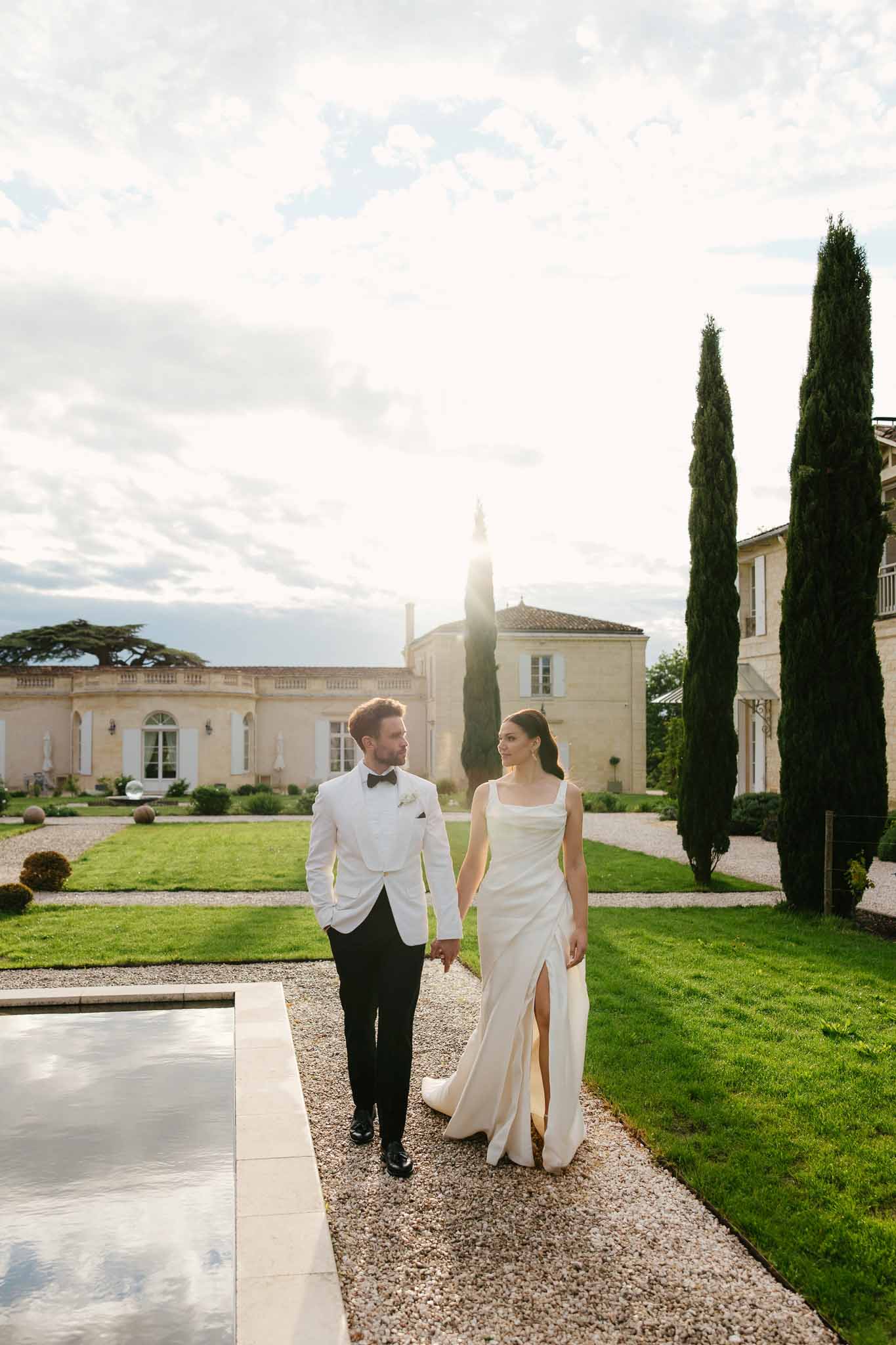 Bride and groom walking hand-in-hand at Mediterranean estate wedding venue with classical architecture