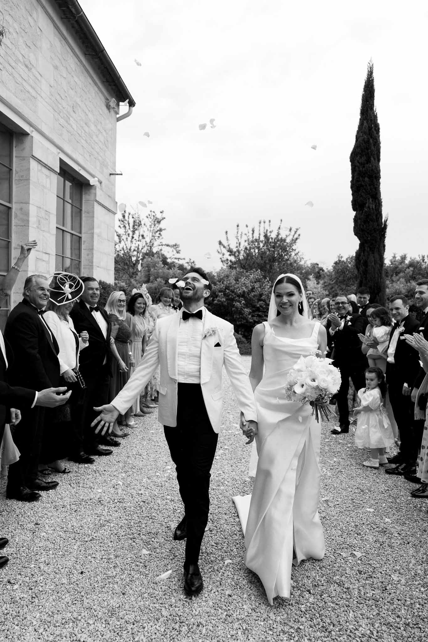 Newlywed couple walking down aisle after ceremony at outdoor courtyard venue with stone building