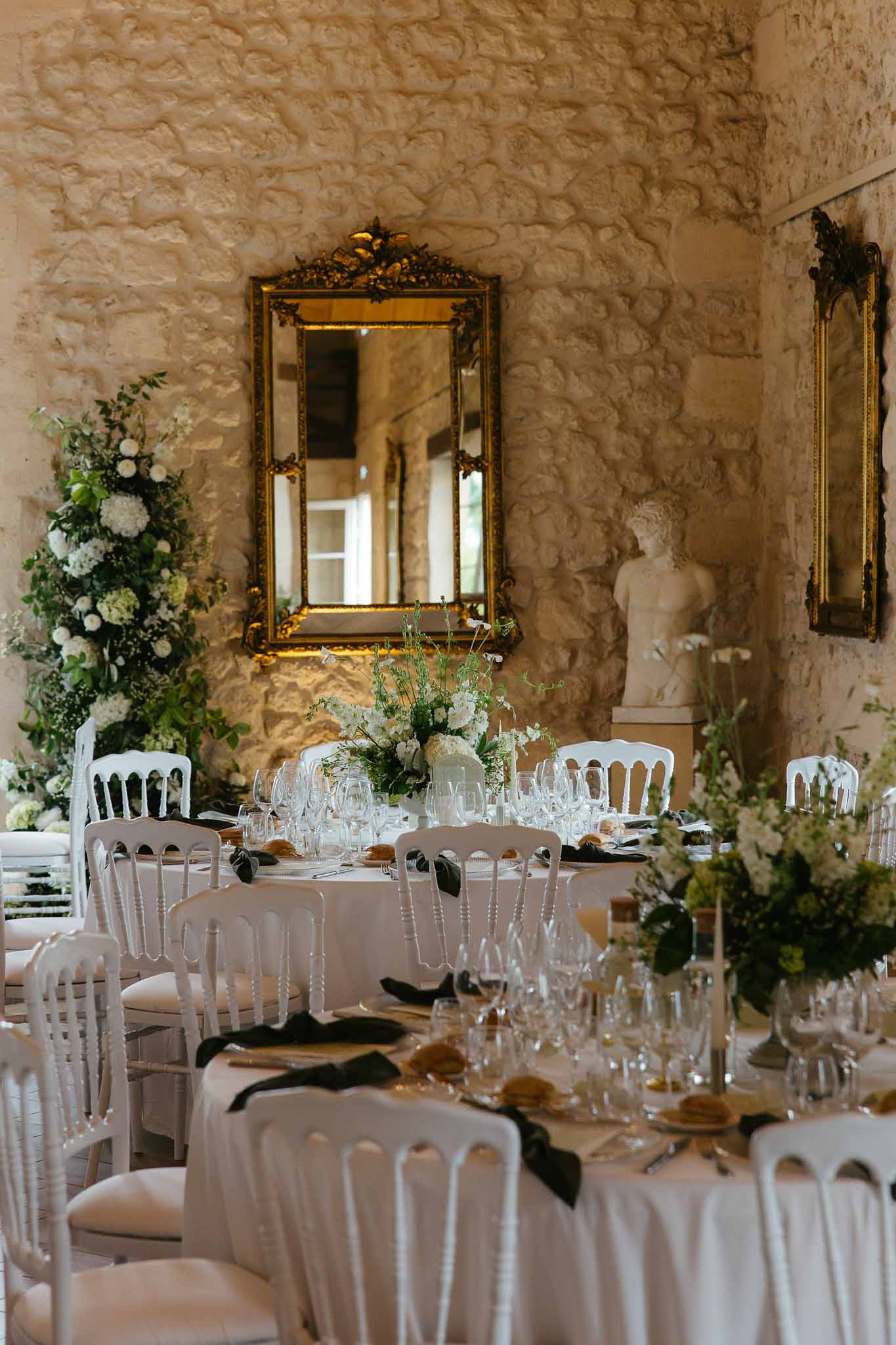 Reception dining room setup with round tables and floral arrangements in indoor stone venue