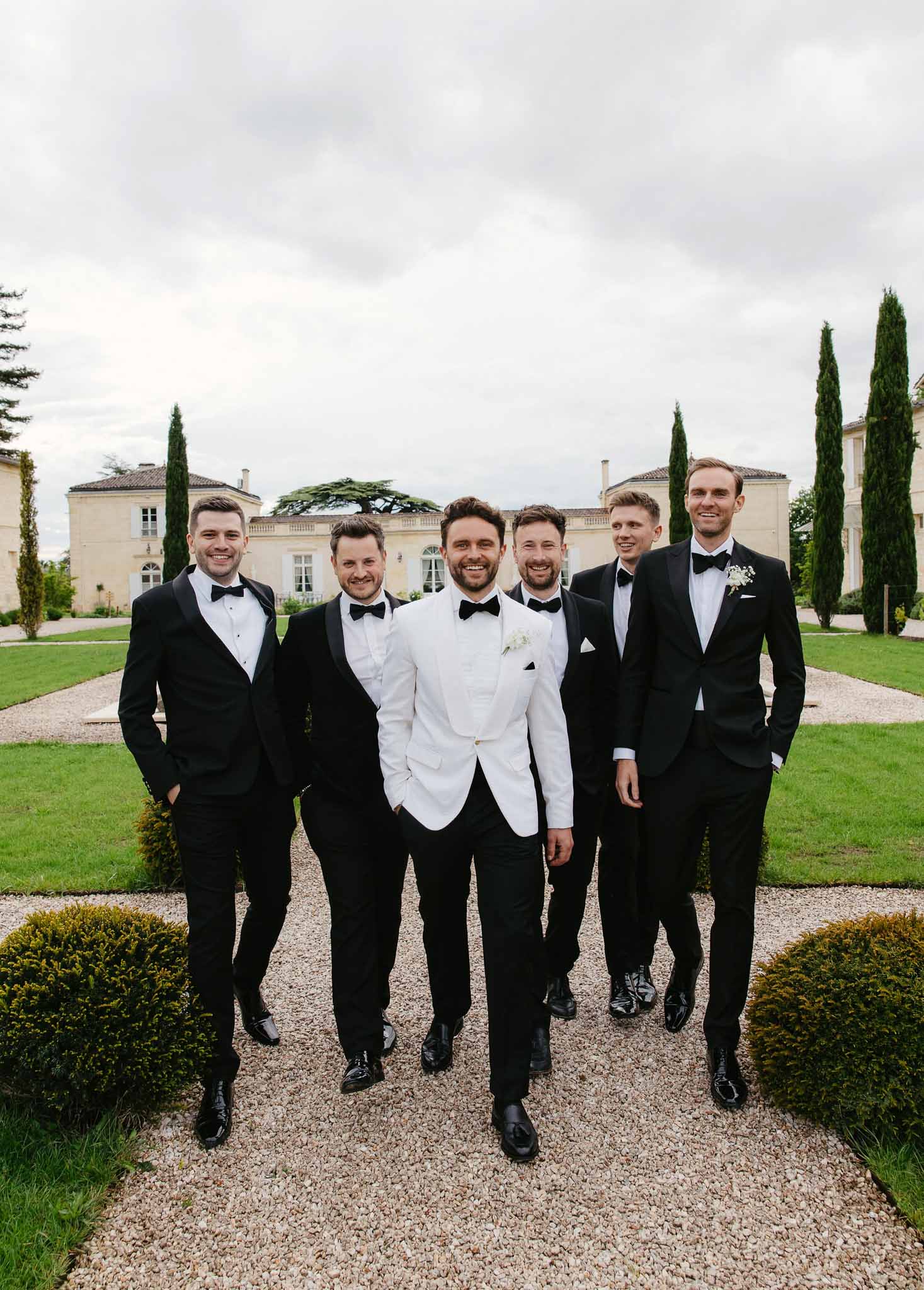 Groom and groomsmen walking together at elegant chateau wedding venue