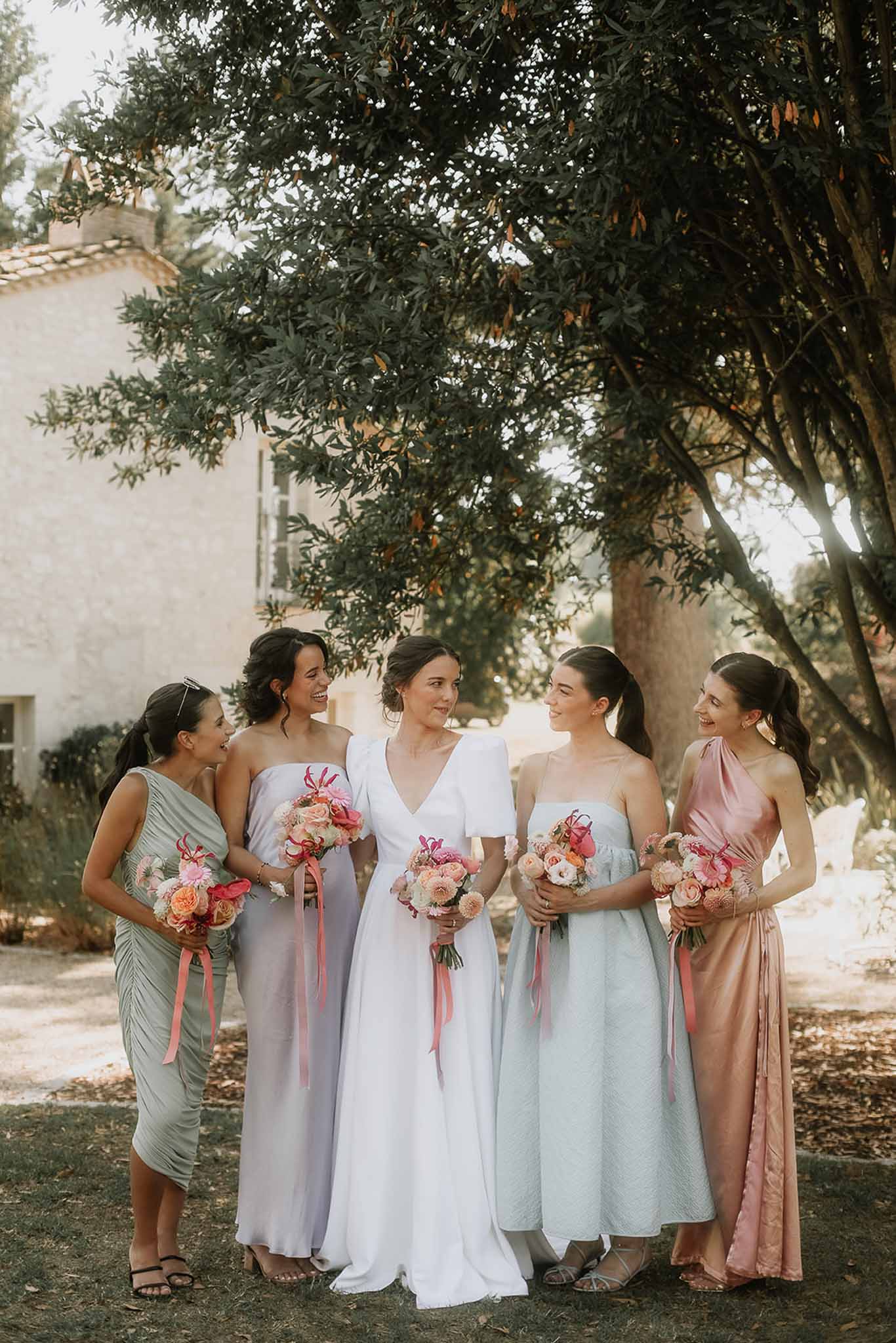 Bride and four bridesmaids with bouquets in Mediterranean courtyard under trees