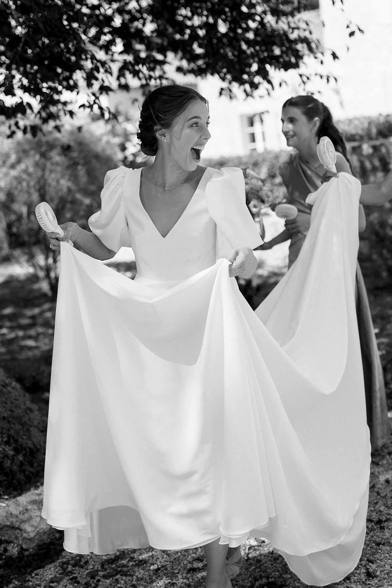 Bride with two bridesmaids holding fans during getting ready moment in garden setting