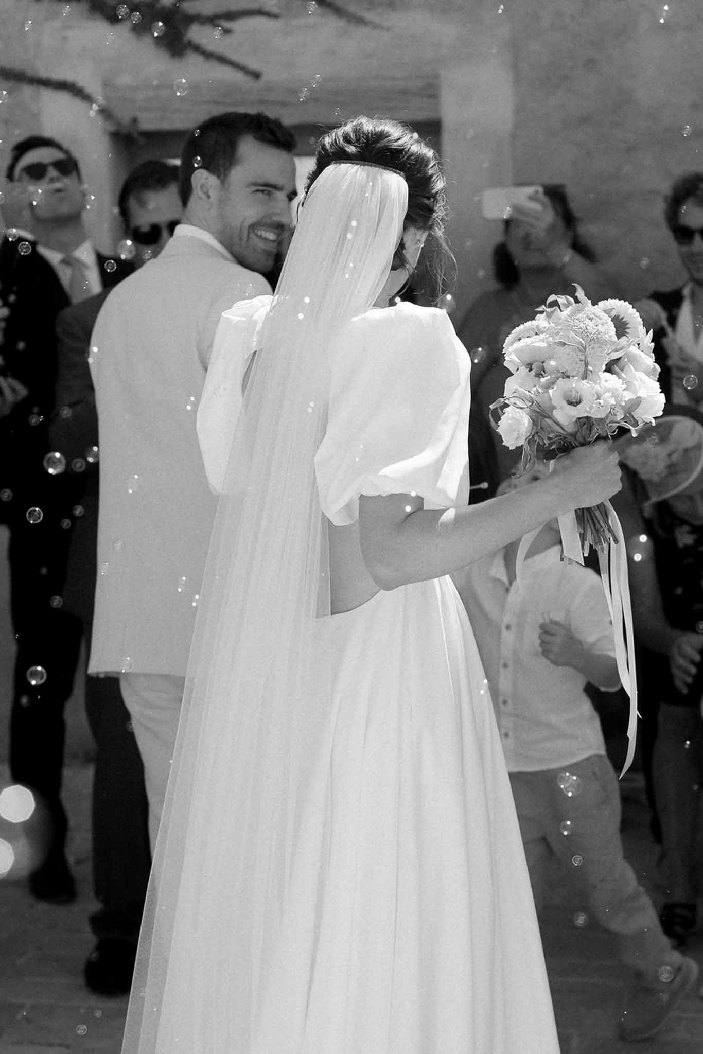 Bride and groom embracing during first dance at indoor wedding venue with guests watching