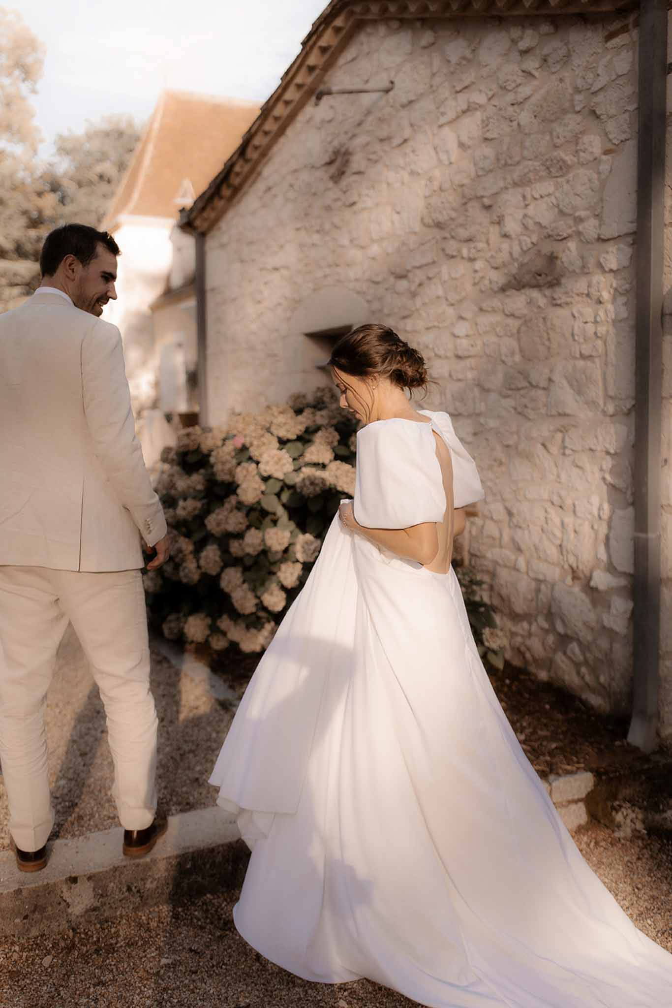 Bride and groom intimate portrait with floral arrangement between rustic stone buildings