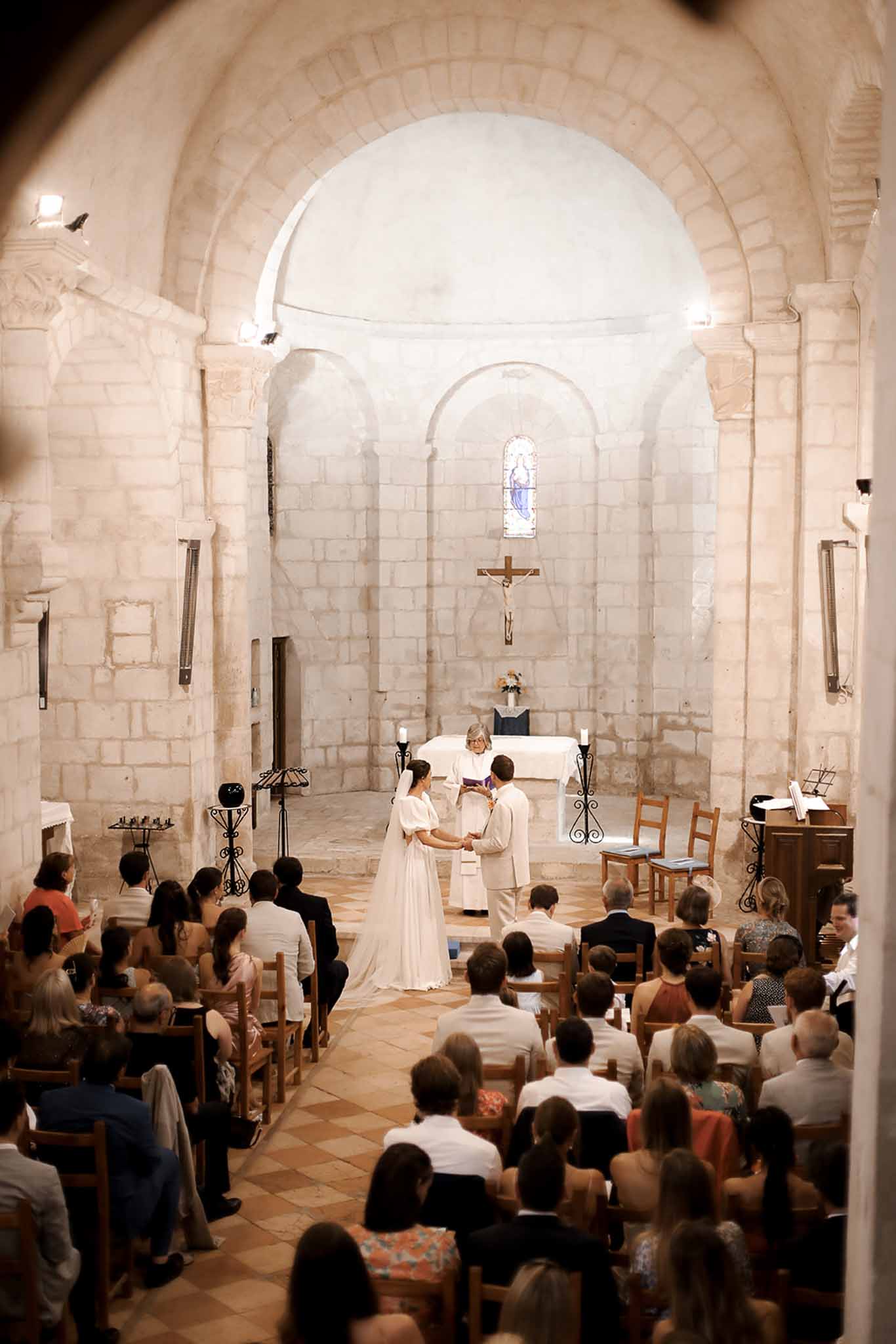 Wedding ceremony in historic stone chapel with Romanesque architecture and natural lighting