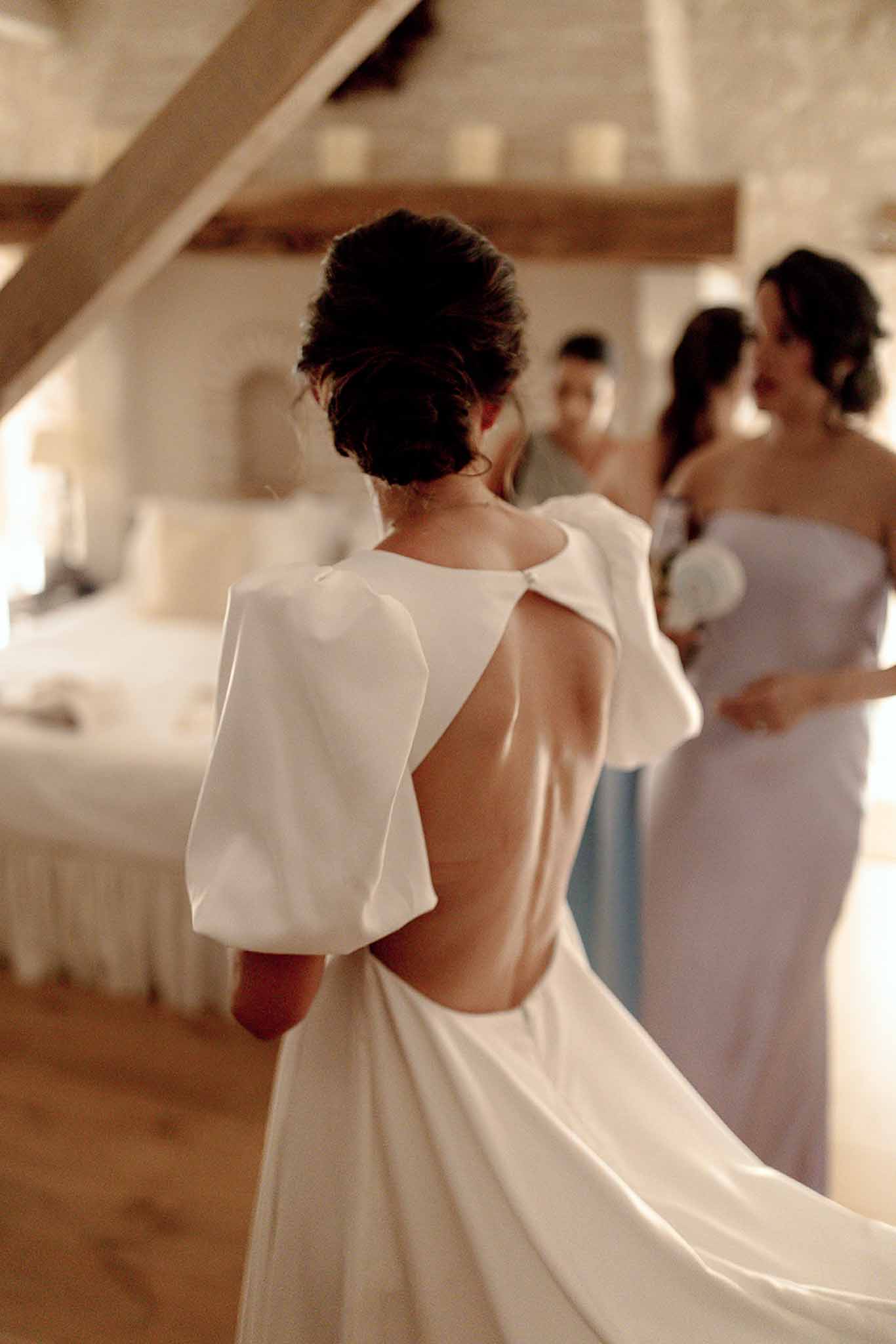 Bride in ivory dress with open back during getting ready moment with bridesmaids in bridal suite