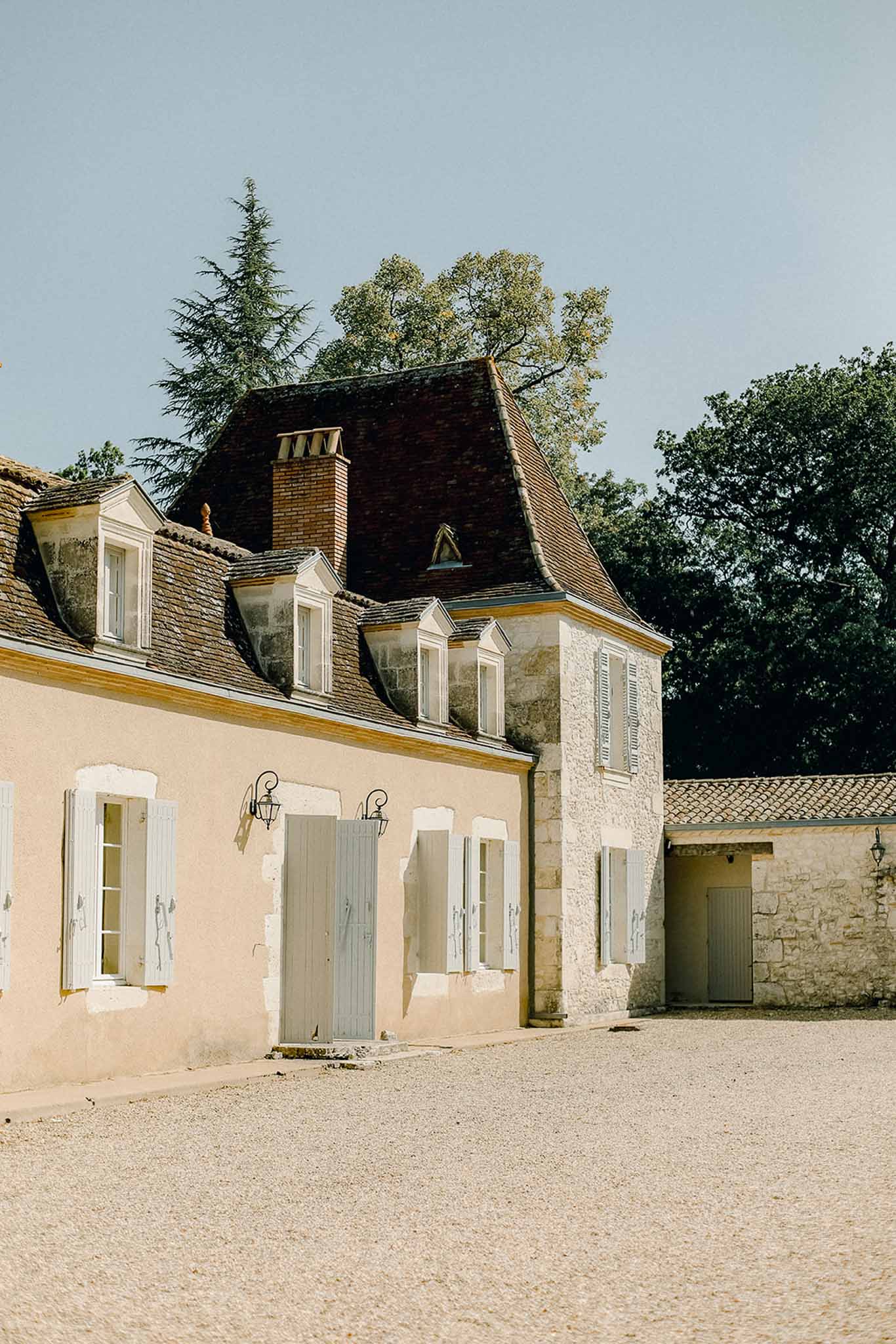 French country wedding venue exterior with peach facade and sage shutters in courtyard setting