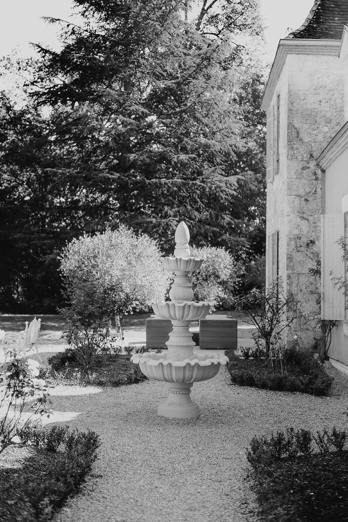 Formal garden courtyard with classical tiered urn and stone building at wedding venue