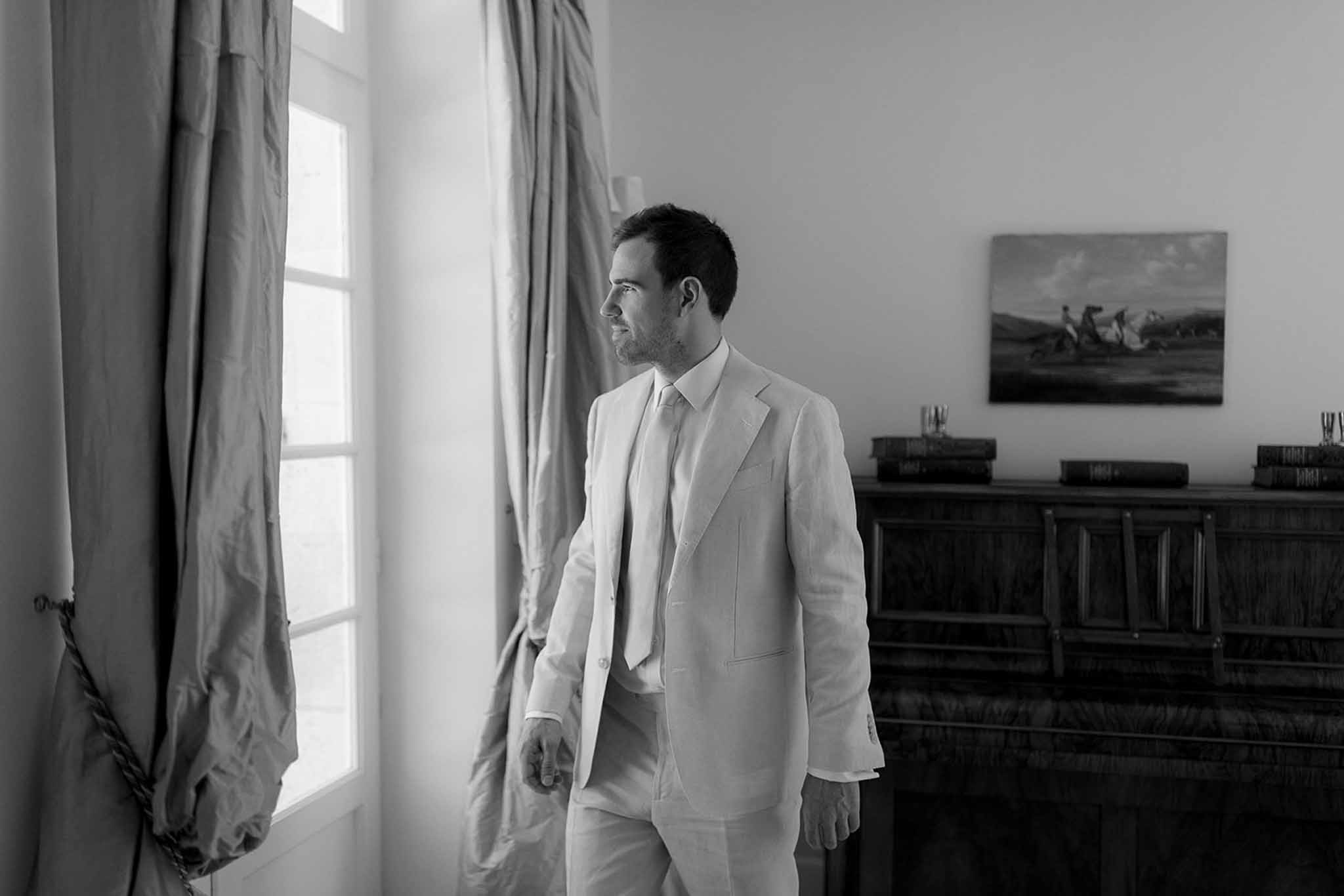Groom in linen suit during getting ready portrait in minimalist indoor room