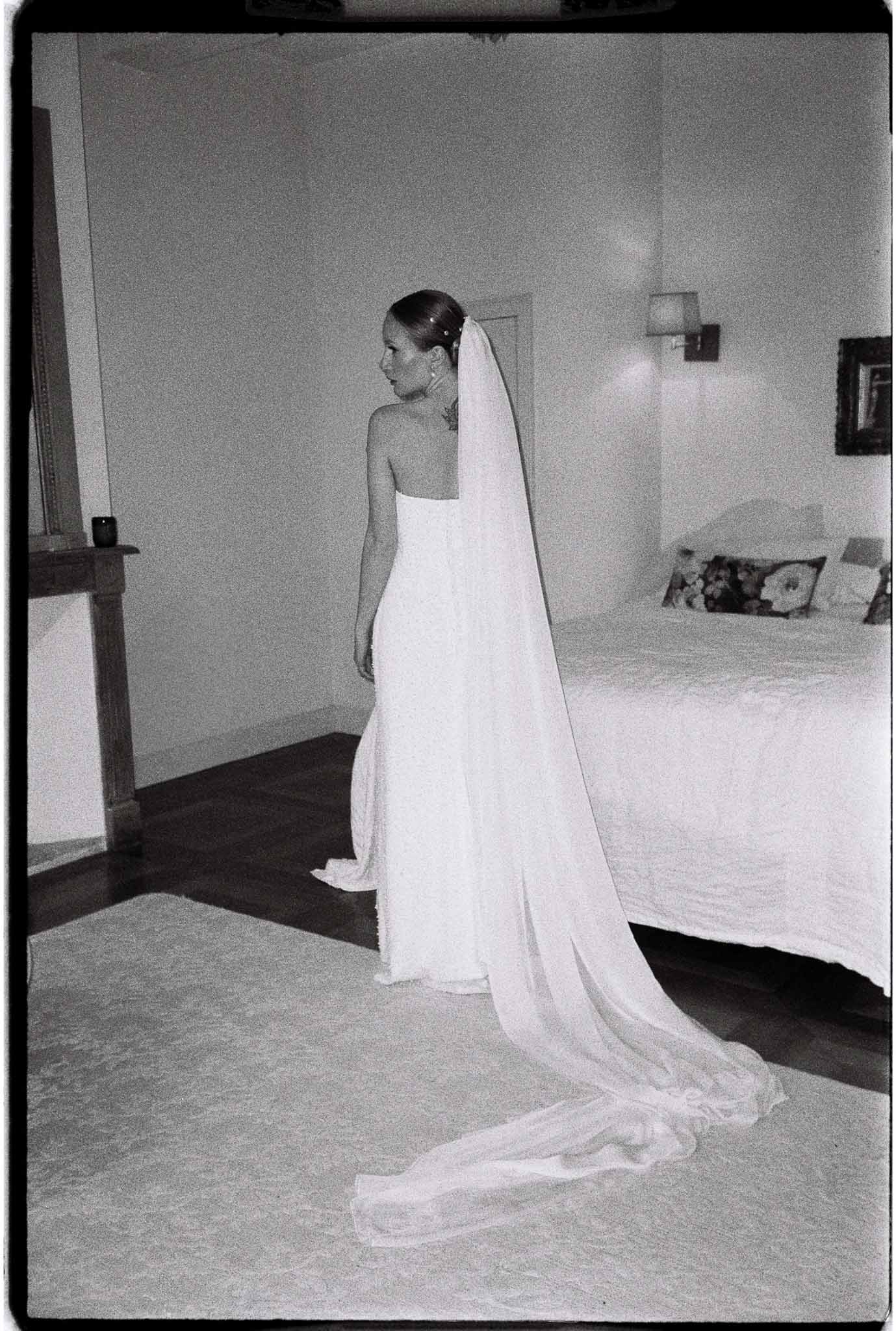 Bride in wedding dress with long train during getting ready moments in bedroom
