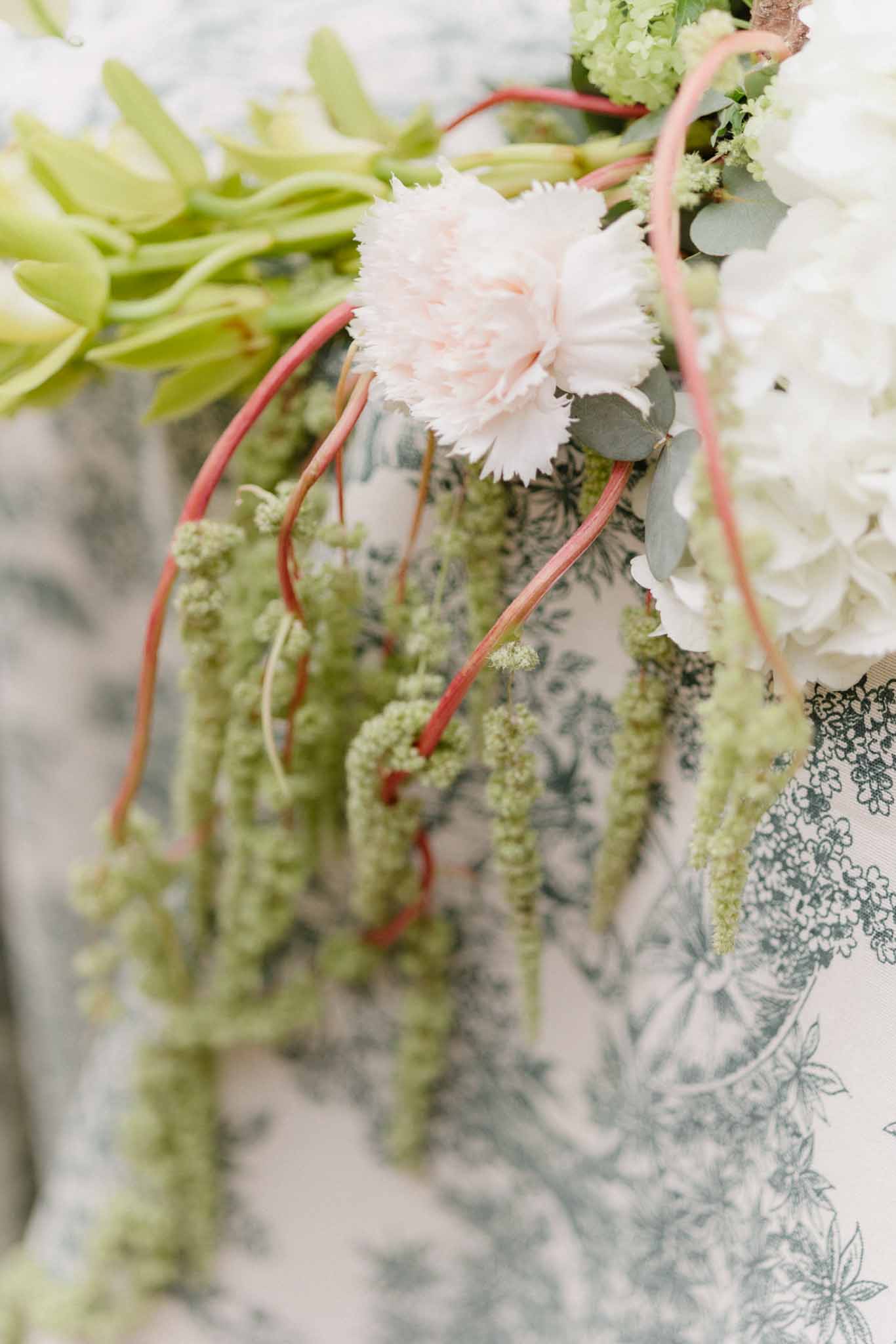 Close-up of bridal bouquet with blush carnations, eucalyptus, and coral willow branches